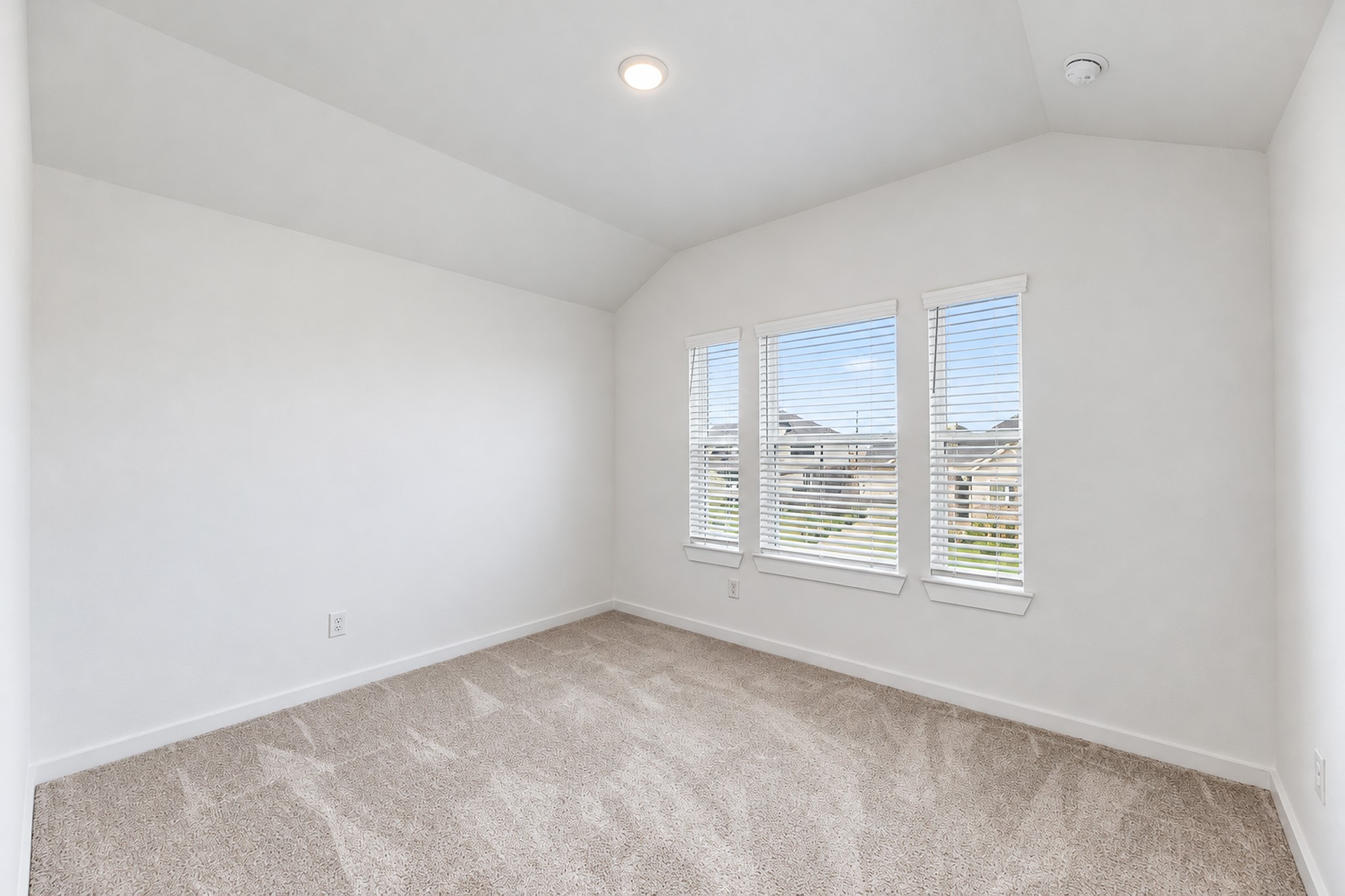 Bright and airy bedroom with plush carpeting and large windows offering a scenic neighborhood view.
