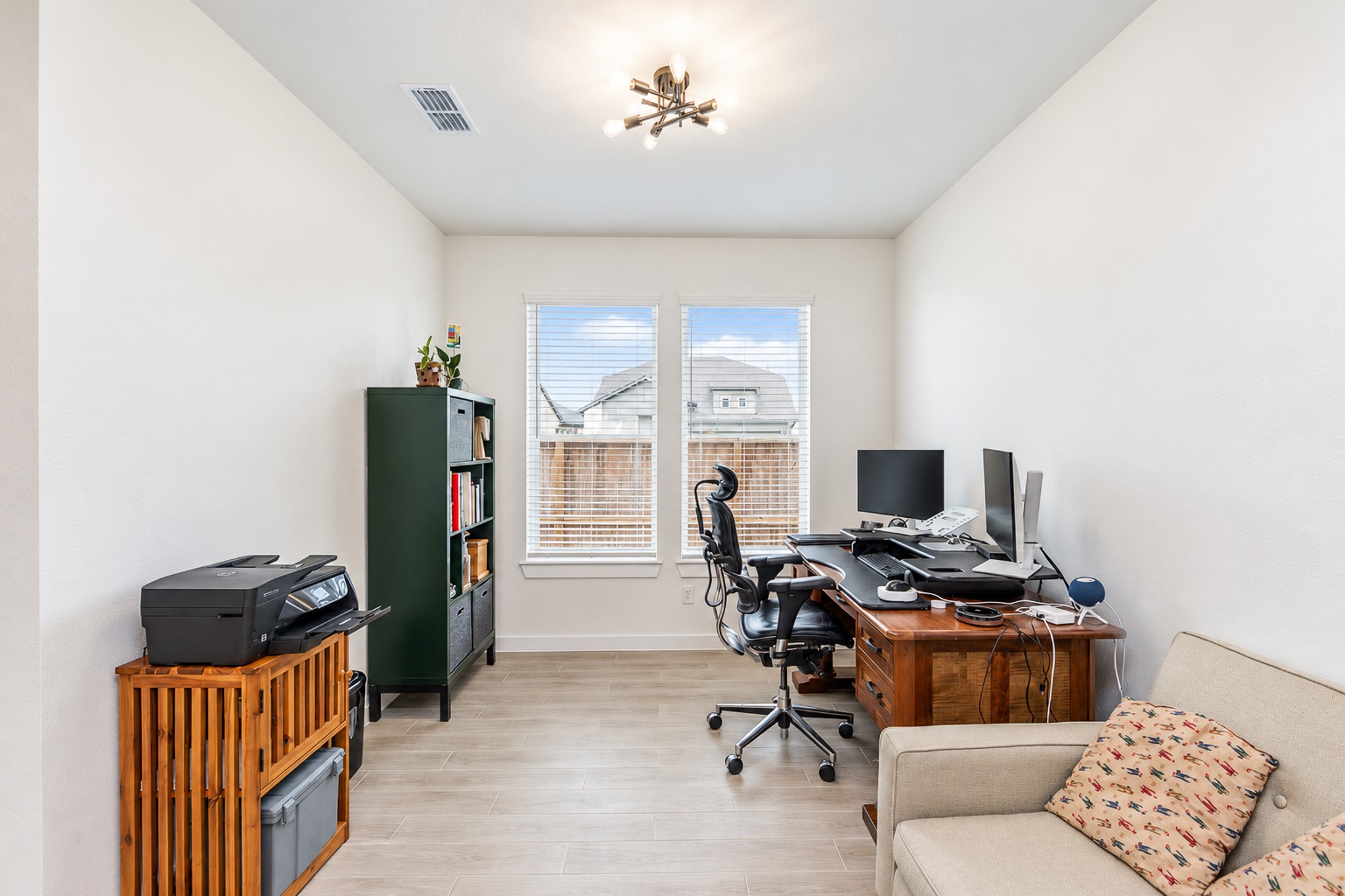 Bright and functional home office featuring large windows, sleek flooring, and ample space for work essentials.