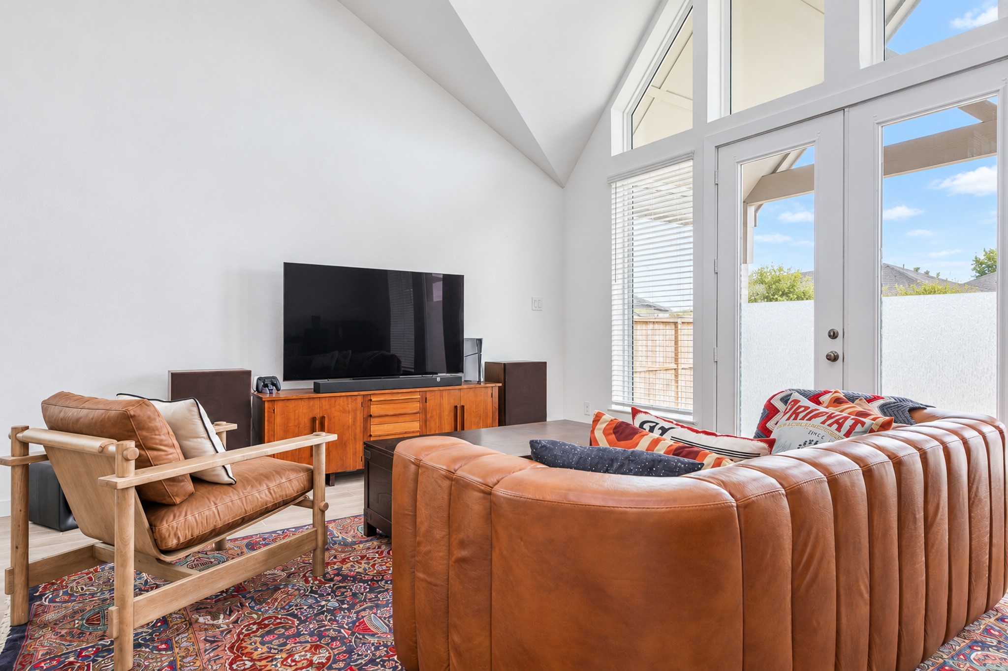 Bright and inviting living room featuring high ceilings, expansive windows, and stylish leather seating, perfect for relaxation and entertainment.