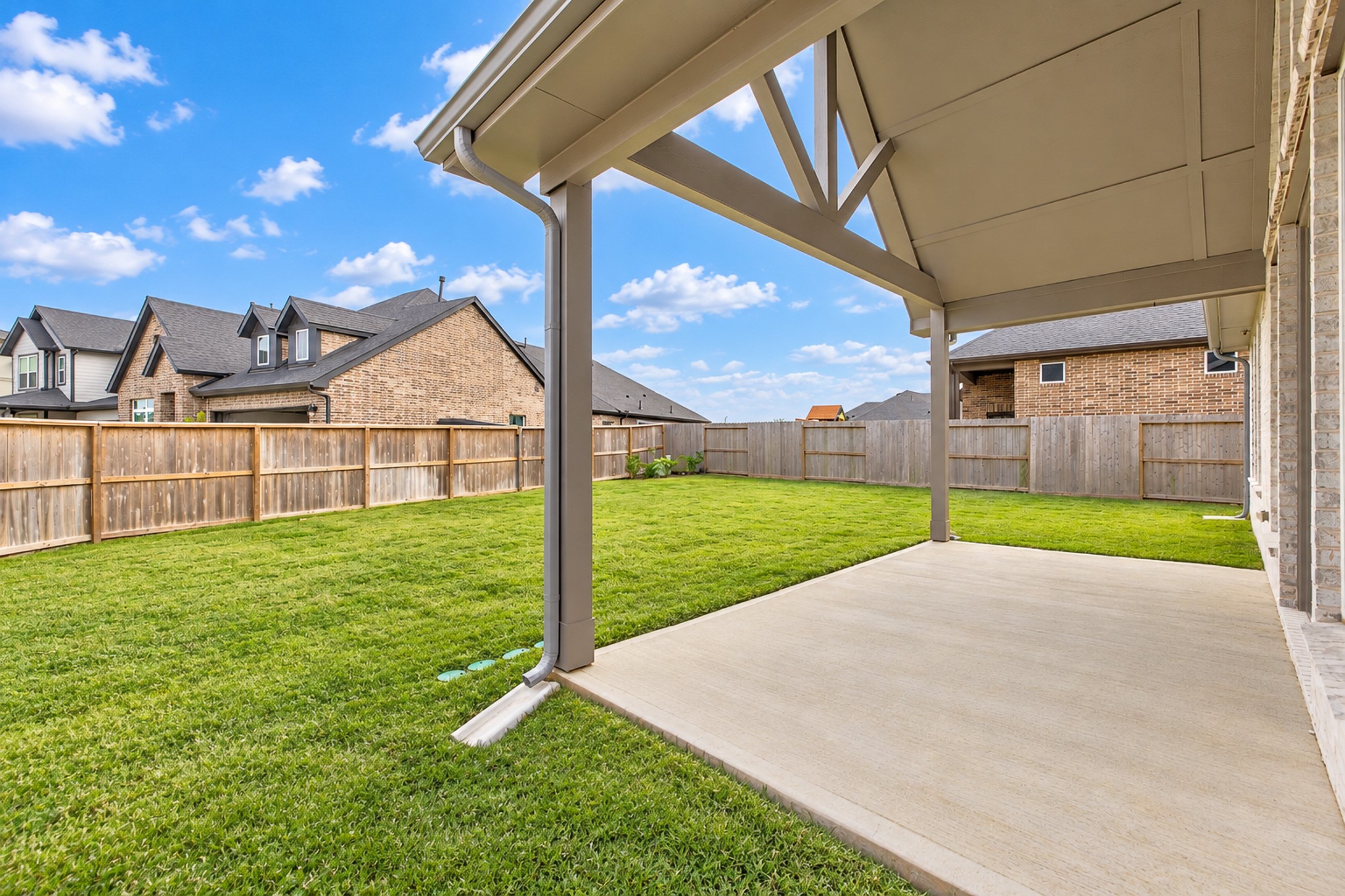Spacious backyard with a covered patio, perfect for outdoor relaxation and entertaining, surrounded by a privacy fence.