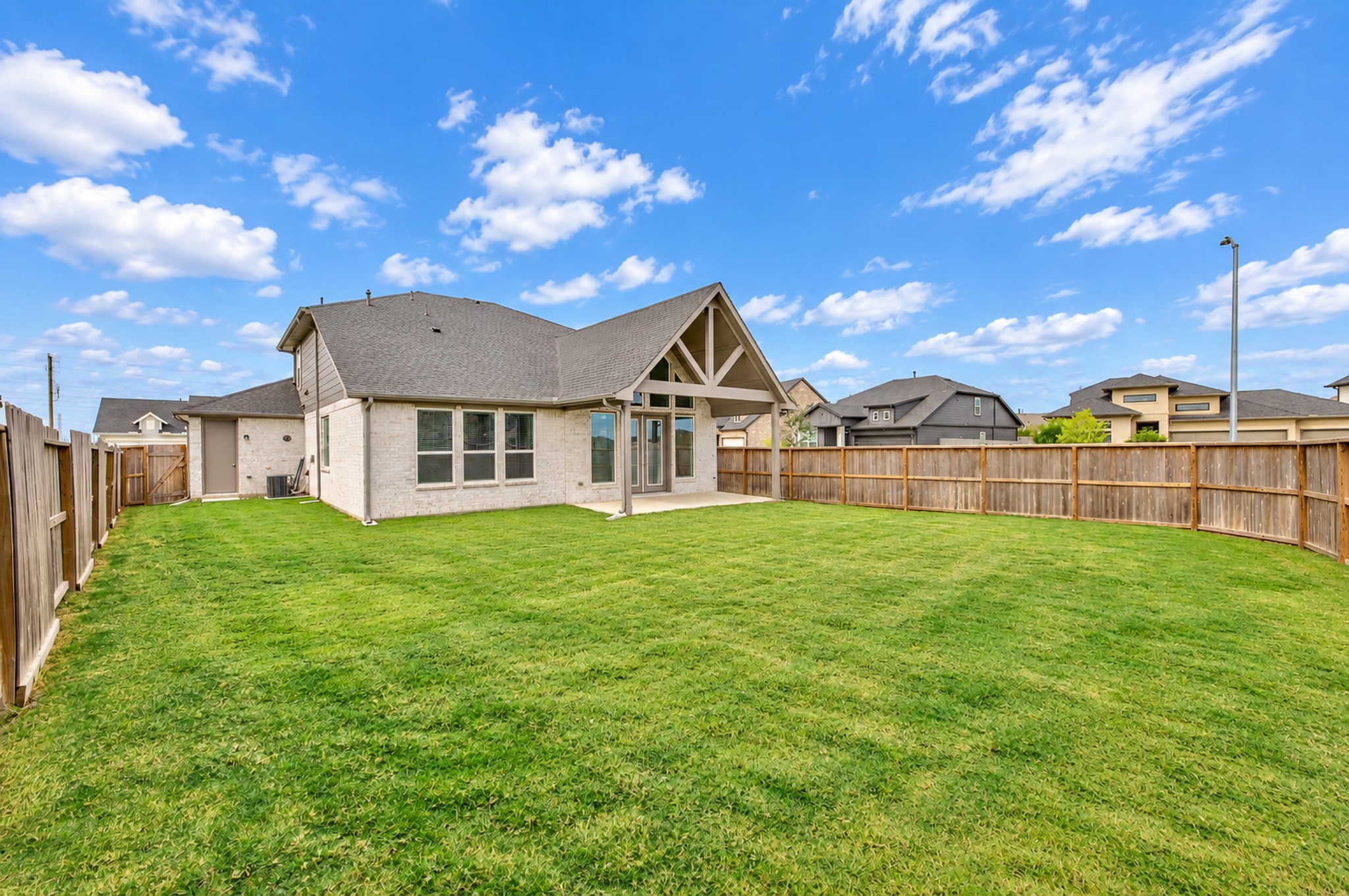 Spacious backyard with a lush green lawn, perfect for outdoor activities, surrounded by a wooden fence for privacy.