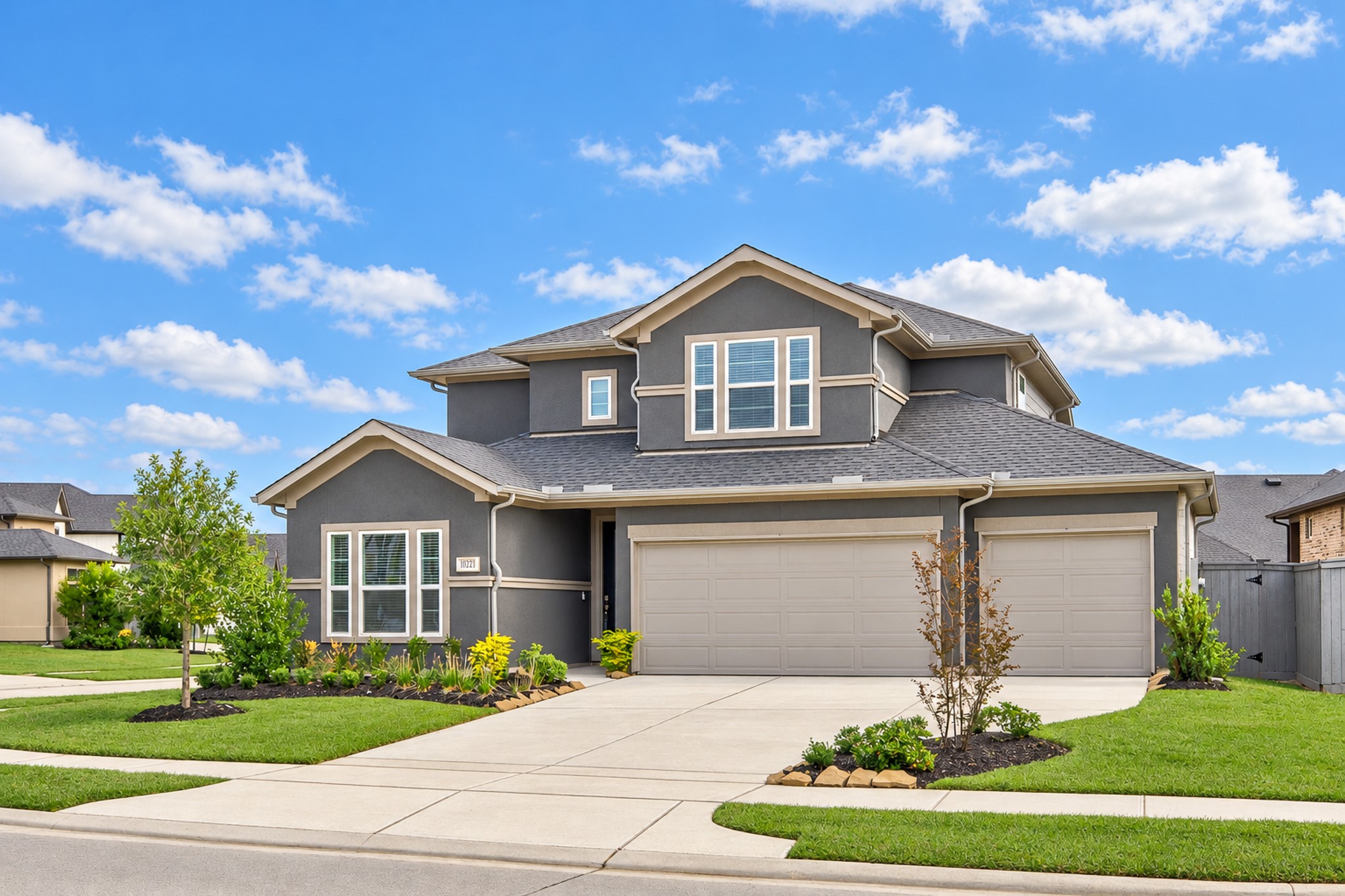 Charming two-story home with a modern exterior and spacious three-car garage, set on a well-maintained corner lot with lush landscaping.