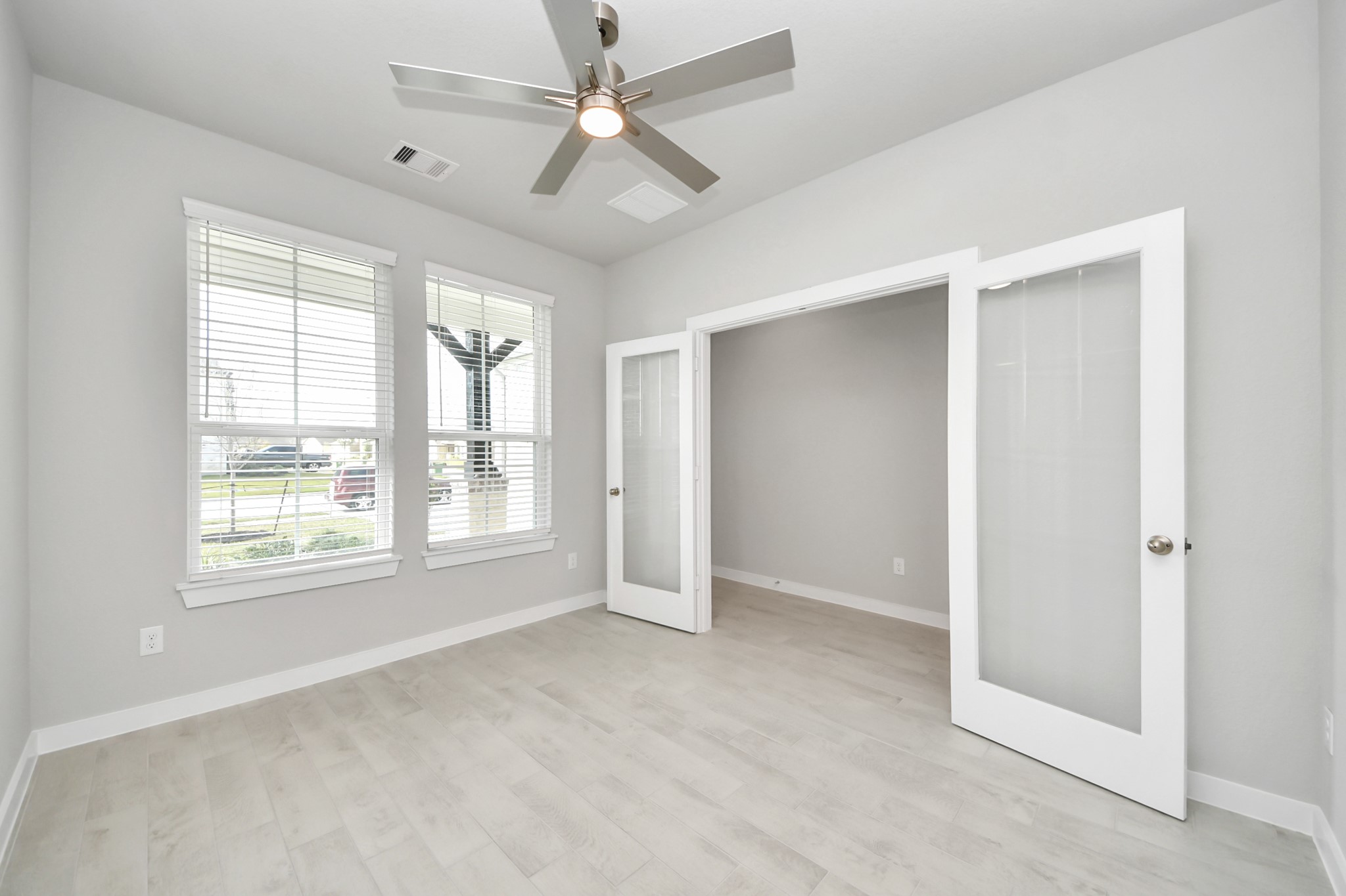 Experience the perfect blend of sophistication and warmth in this home office, boasting elegant wood-look tile flooring and flooded with natural light from expansive windows and French doors. Sample photo of completed home with similar floor plan. Actual colors and selections may vary.
