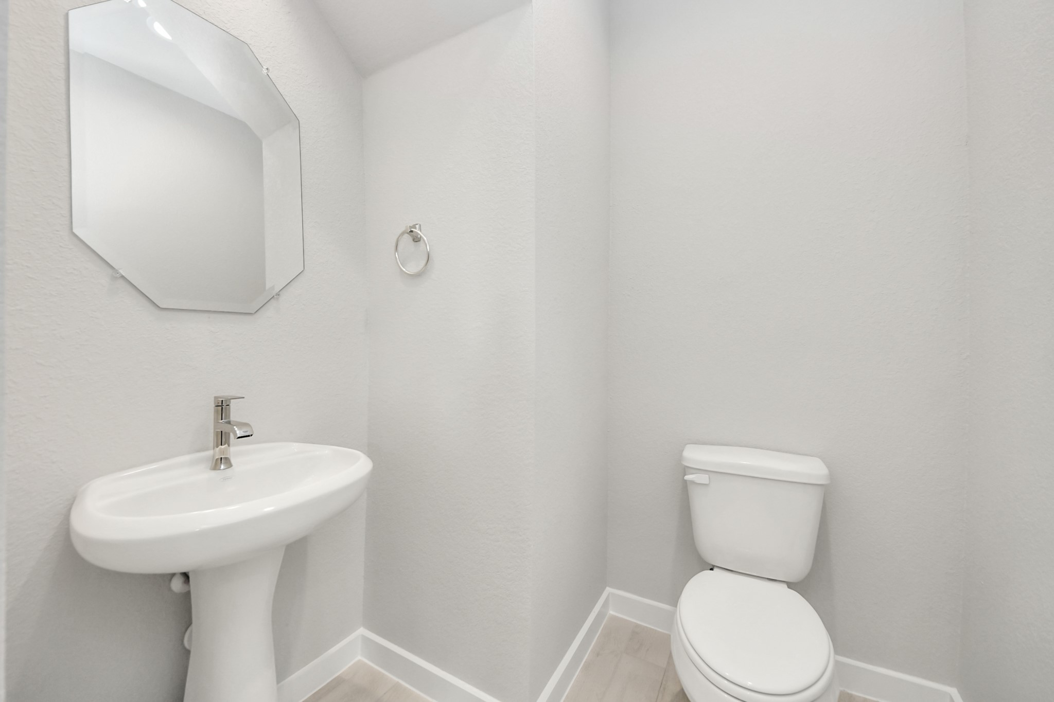 This half bathroom features a stylish pedestal sink, modern hardware, and bright recessed lighting, creating a sleek and inviting space. Sample photo of completed home with similar floor plan. Actual colors and selections may vary.