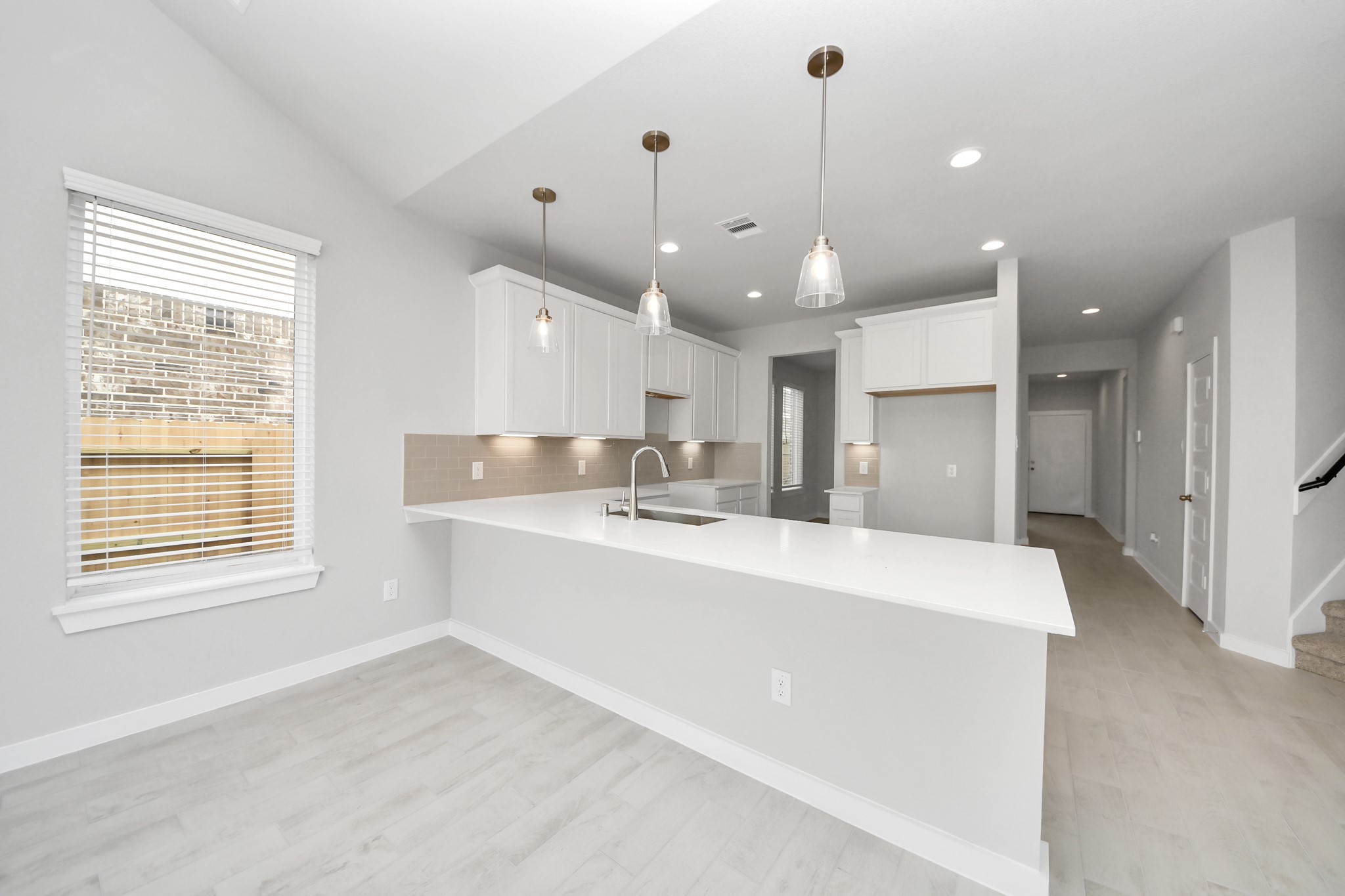 This kitchen is truly a chef's dream! This haven Boasts high ceilings, recessed & pendant lighting, stained wood cabinets, granite countertops, stainless steel appliances, a modern tile backsplash.  All of this overlooks your expansive family room, creating a perfect space for culinary delights and family gatherings. Sample photo of completed home with similar floor plan. Actual colors and selections may vary.