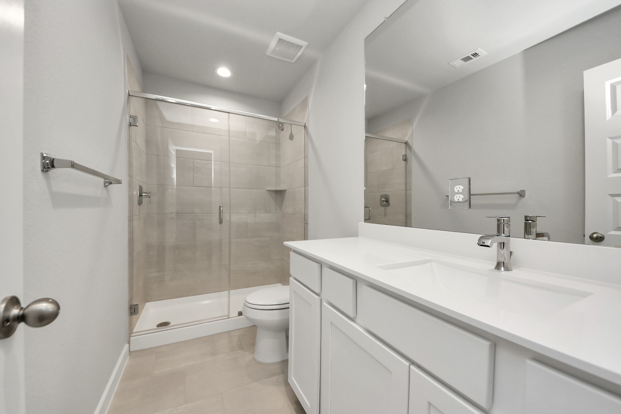 Secondary bath features tile flooring, walk-in shower with tile surround, light stained wood cabinets, beautiful light countertop. Sample photo of completed home with similar floor plan. Actual colors and selections may vary.