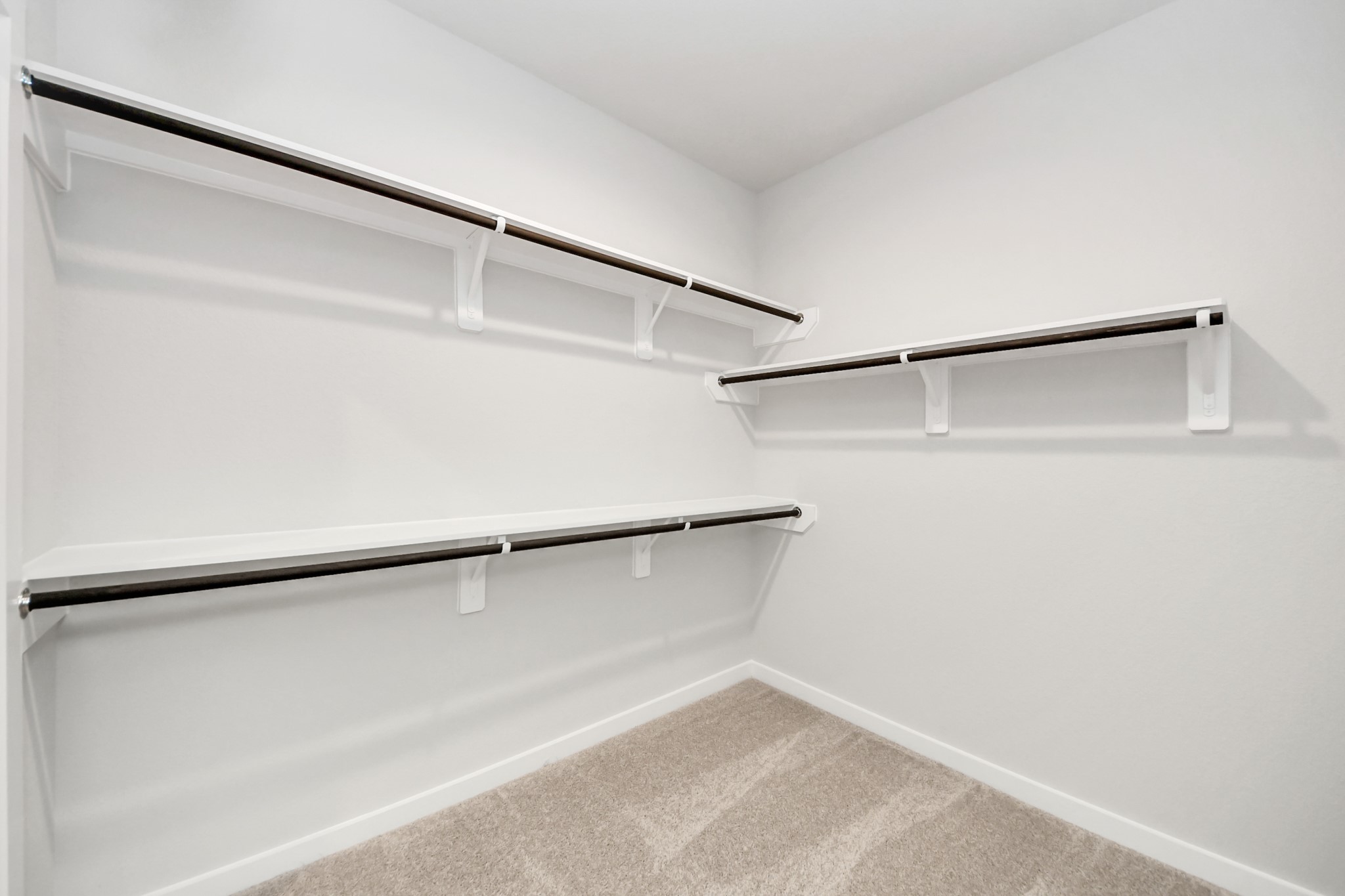 Walk-in closet that epitomizes luxury and practicality. This generously sized space features built-in shelving, offering abundant room for impeccable organization. High ceilings and recessed lighting create a bright and welcoming ambiance. Sample photo of completed home with similar floor plan. Actual colors and selections may vary.