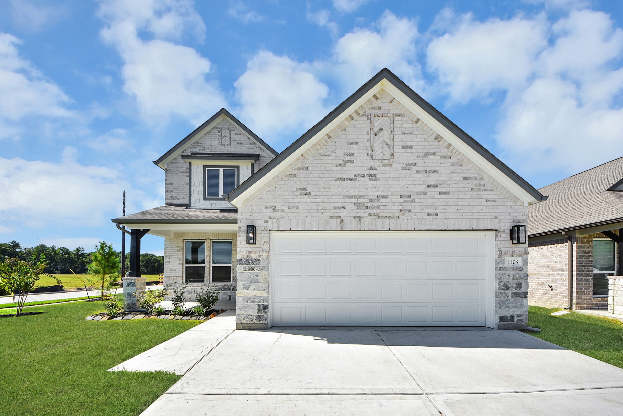 Meticulously maintained yard and lush landscape, paired with a premium elevation featuring captivating brick accents. Modern coach lights add a touch of contemporary elegance to the exterior.