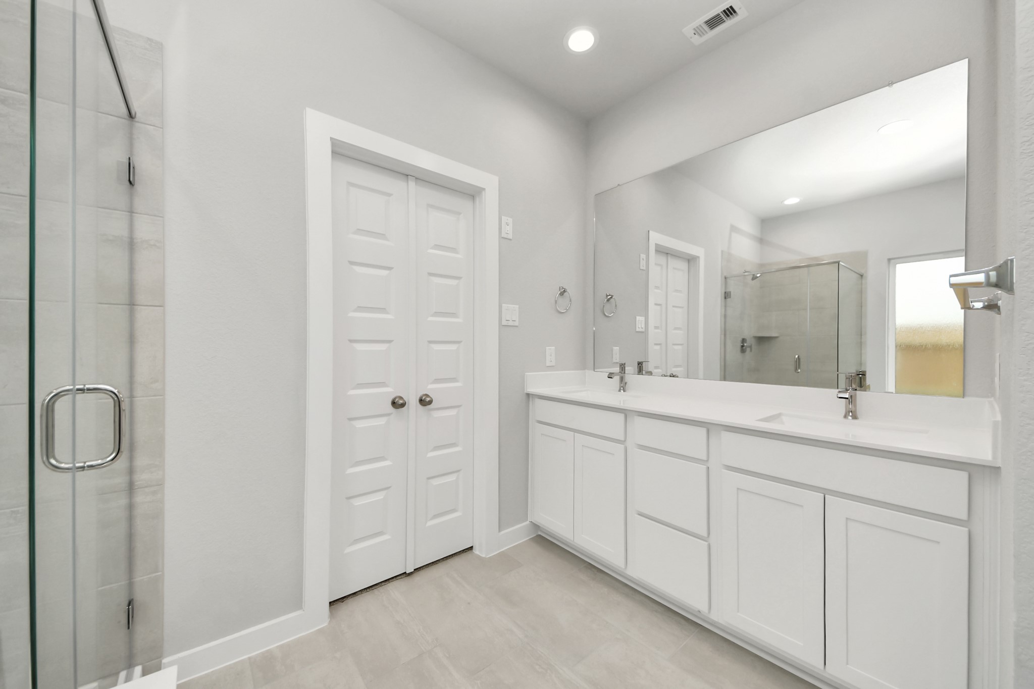 Elevate your daily routine at the elegant vanity, now equipped with double sinks, light countertops, modern hardware, and beautiful recessed lights. Sample photo of completed home with similar floor plan. Actual colors and selections may vary.