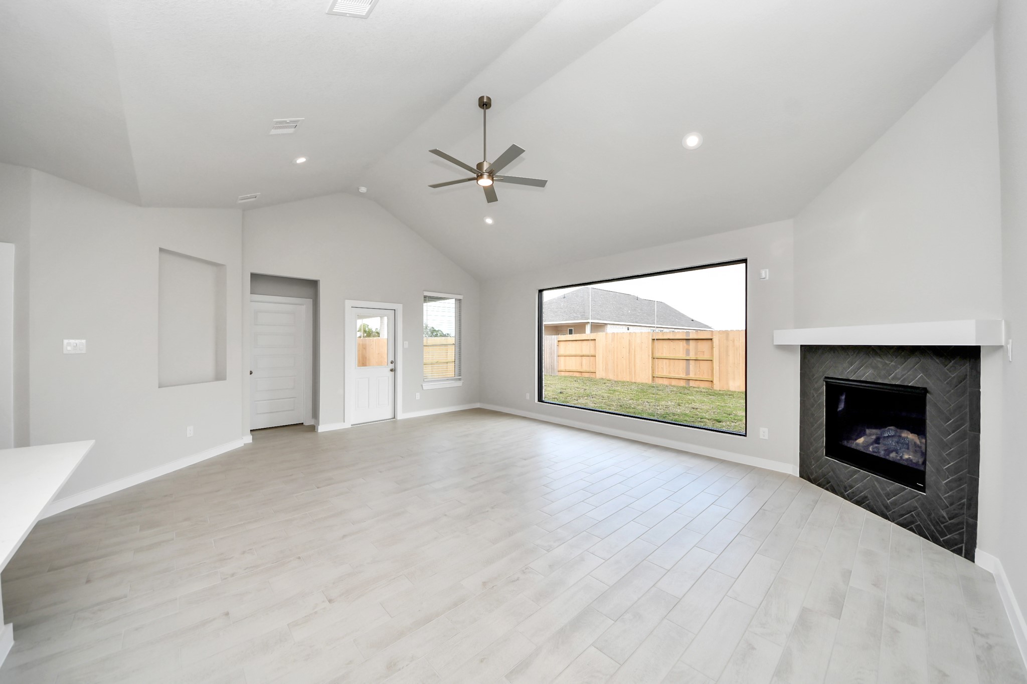 Welcome family and guests to your charming living room! With its high ceilings, recessed lighting, ceiling fan, custom paint, beautiful flooring, and large windows that let in abundant natural light, this room is perfect for gatherings. Sample photo of completed home with similar floor plan. Actual colors and selections may vary.
