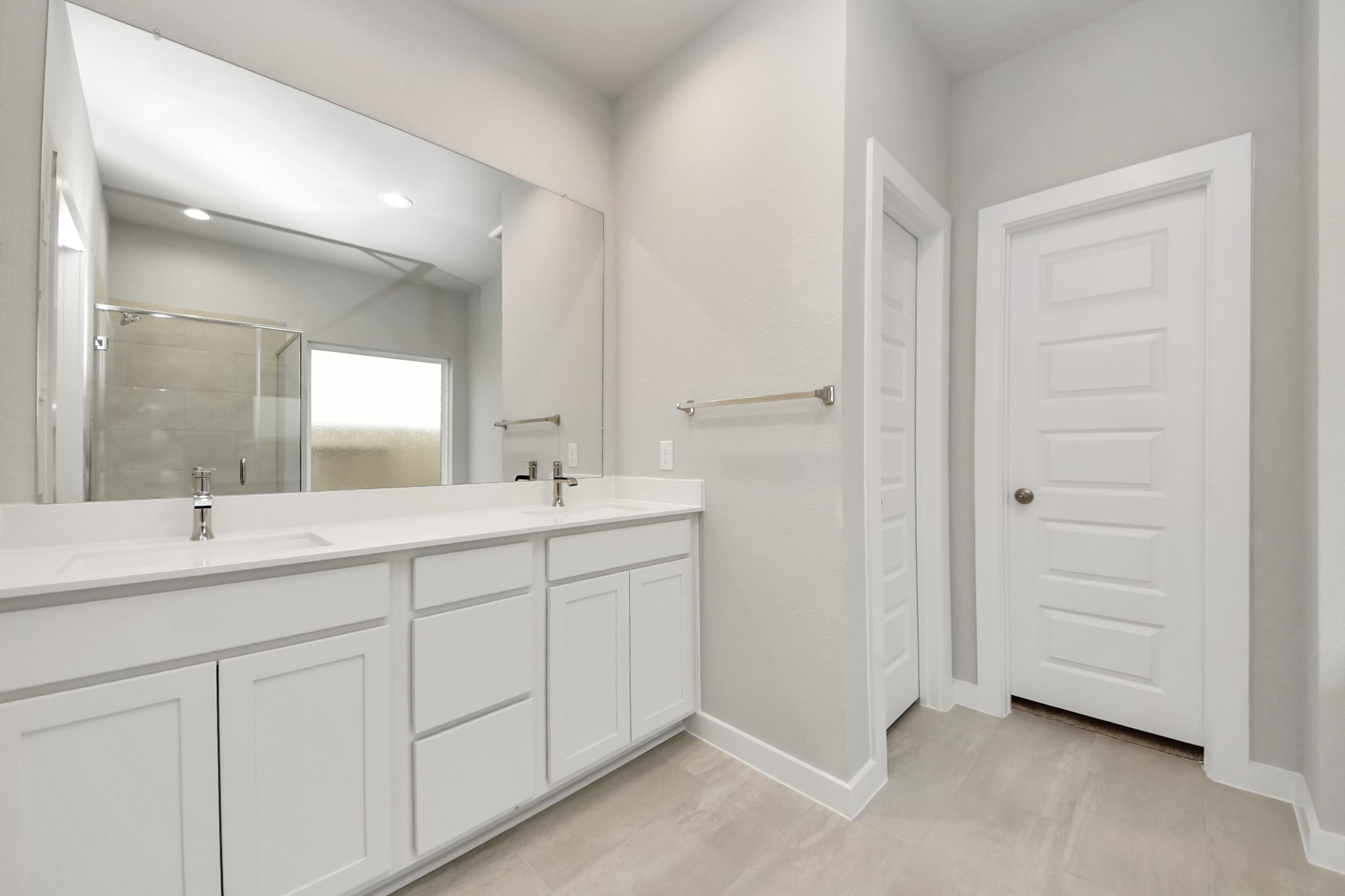 Escape to a spa-like oasis in this primary bathroom. Enjoy a walk-in shower with tile surround, a separate garden tub with custom detailing, and an elegant vanity featuring light countertops, modern hardware, and beautiful recessed lights. Experience luxury and relaxation in every detail. Sample photo of completed home with similar floor plan. Actual colors and selections may vary.