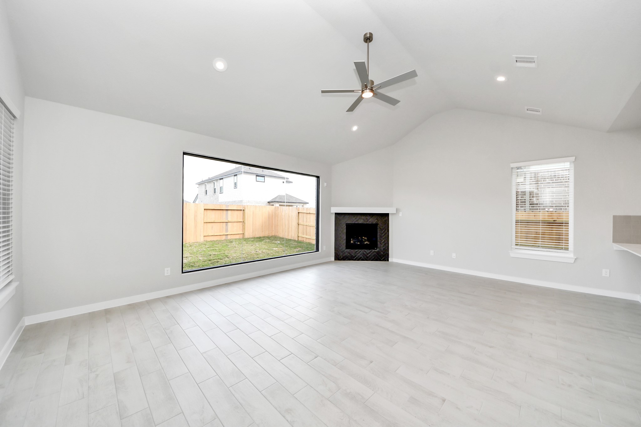 Family room flooded with natural light through the expansive windows.  The premium tile flooring adds a touch of luxury to the space, creating the perfect setting for relaxing moments and cherished gatherings with loved ones. Sample photo of completed home with similar floor plan. Actual colors and selections may vary.