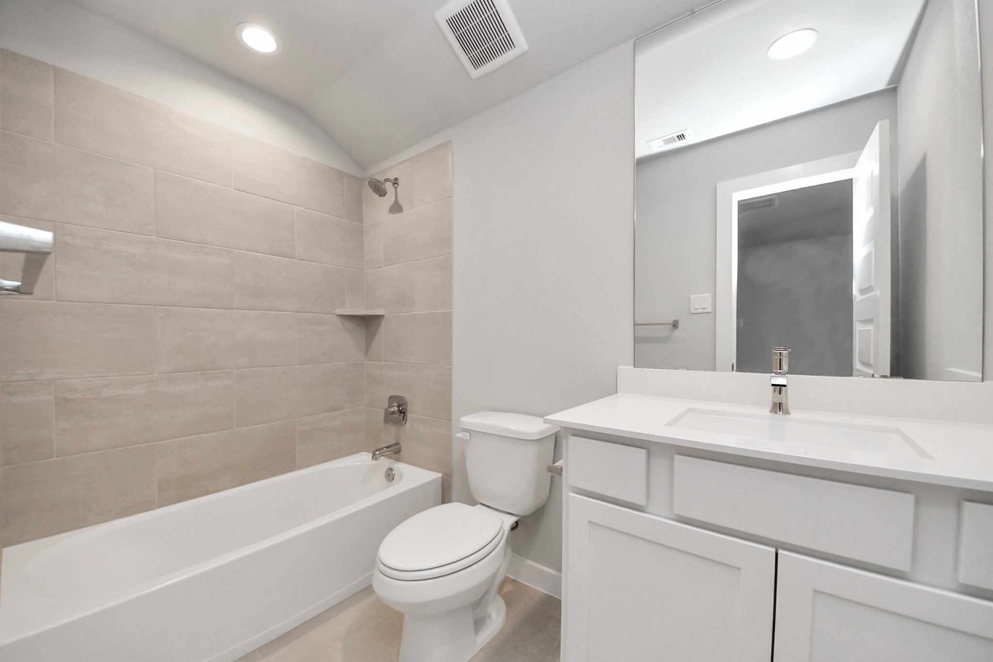 Secondary bath features tile flooring, bath/shower combo with tile surround, light stained wood cabinets, beautiful light countertop. Sample photo of completed home with similar floor plan. Actual colors and selections may vary.