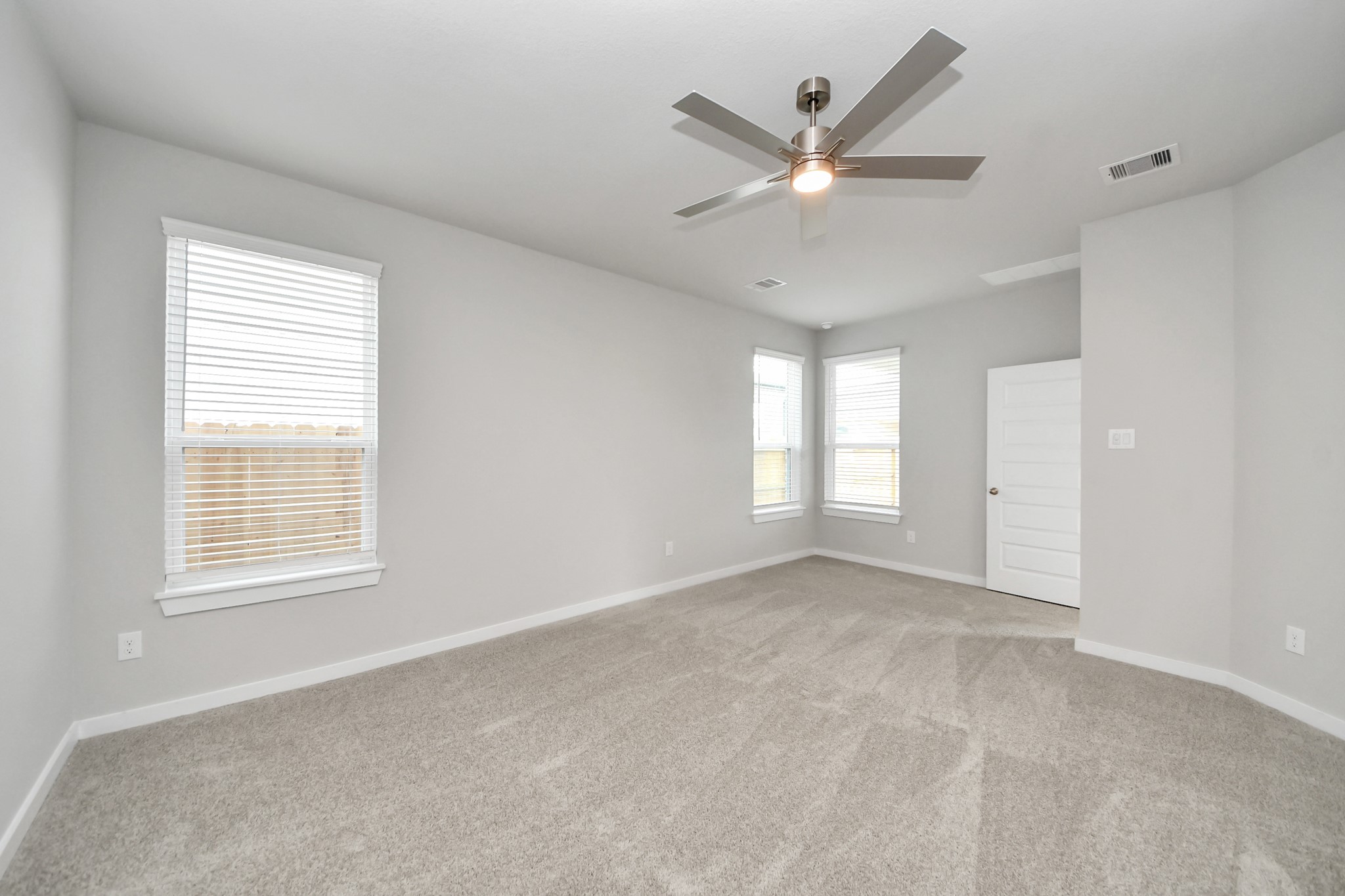 Escape and relax in the exquisite primary suite, a haven to unwind after a long day. The spacious room, boasts plush carpeting, soothing paint tones, high ceilings, and expansive windows adorned with privacy blinds. Sample photo of completed home with similar floor plan. Actual colors and selections may vary.