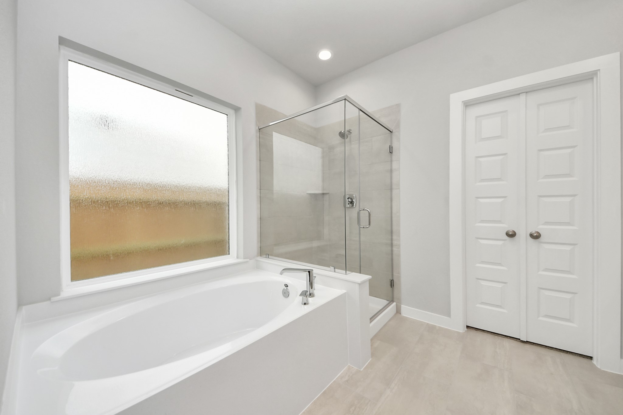 Indulge in a spa-like retreat within the confines of this primary bathroom. Delight in a spacious walk-in shower enveloped in stylish tile surround and unwind in a separate garden tub adorned with custom detailing. Sample photo of completed home with similar floor plan. Actual colors and selections may vary.