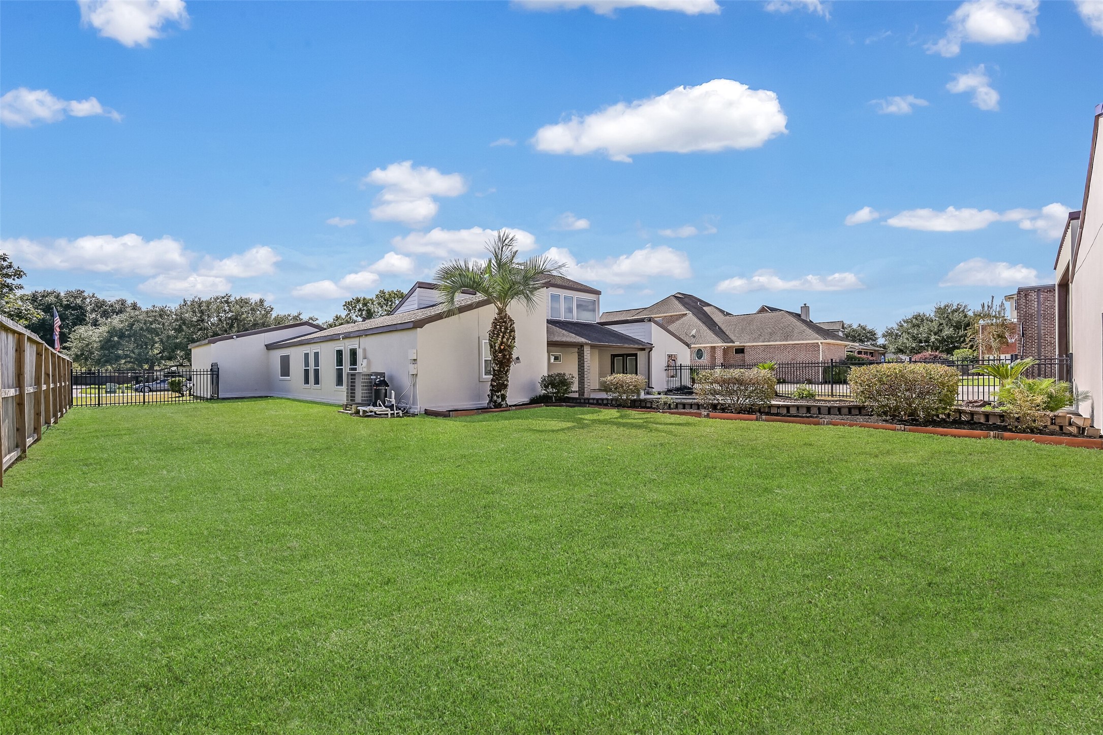 A generous grassy backyard offers additional outdoor space beyond the swimming pool and covered patio. Mature landscaping, a palm tree & fenced boundaries complement the setting, while the home's distinctive architecture and adjoining aviation facilities make this property truly unique.