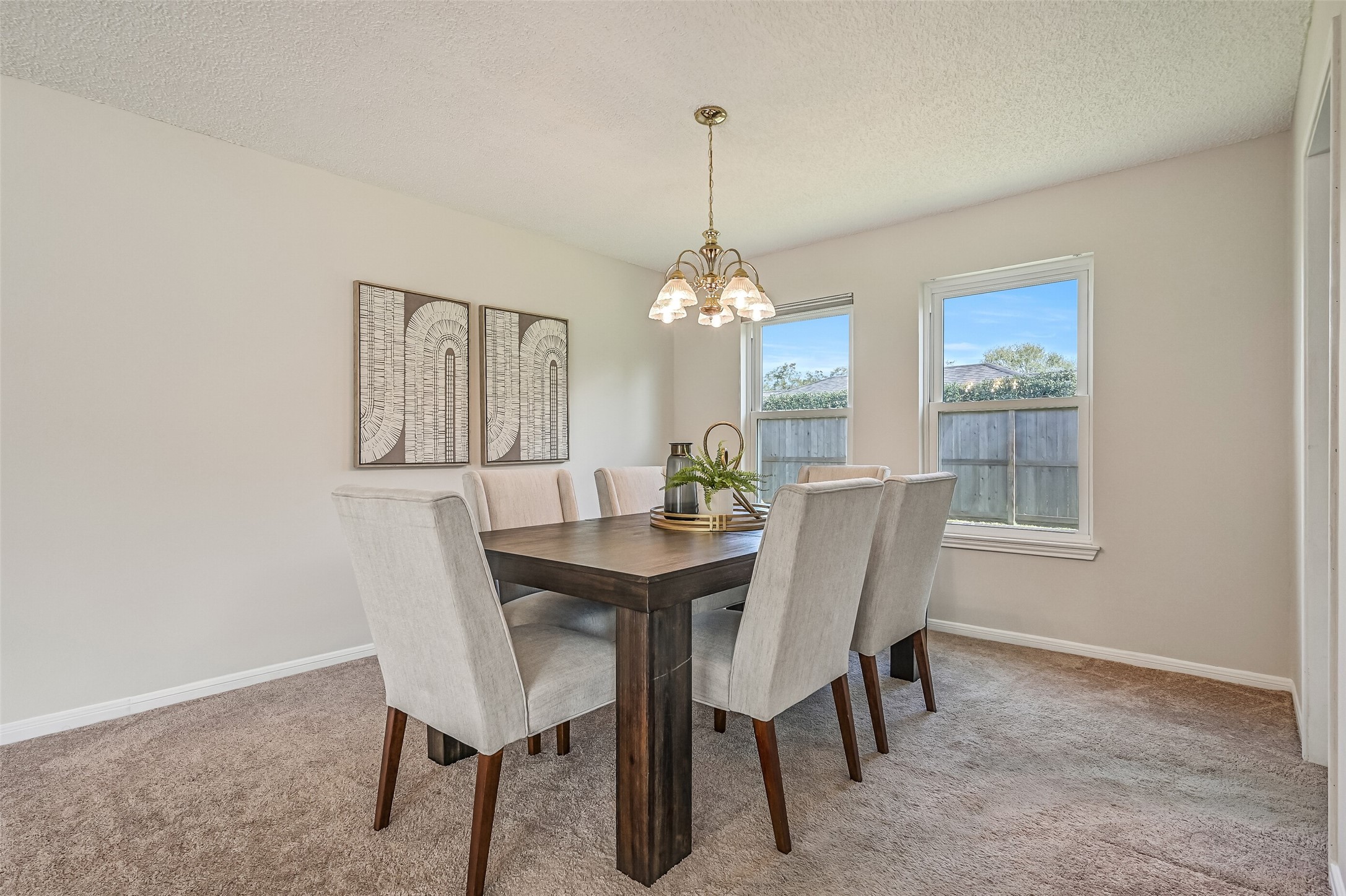 The formal dining room offers a comfortable setting for gatherings, with soft neutral carpeting, a traditional chandelier & two windows overlooking the backyard. Conveniently positioned beside the kitchen, this dedicated dining space easily accommodates a full-size dining table.