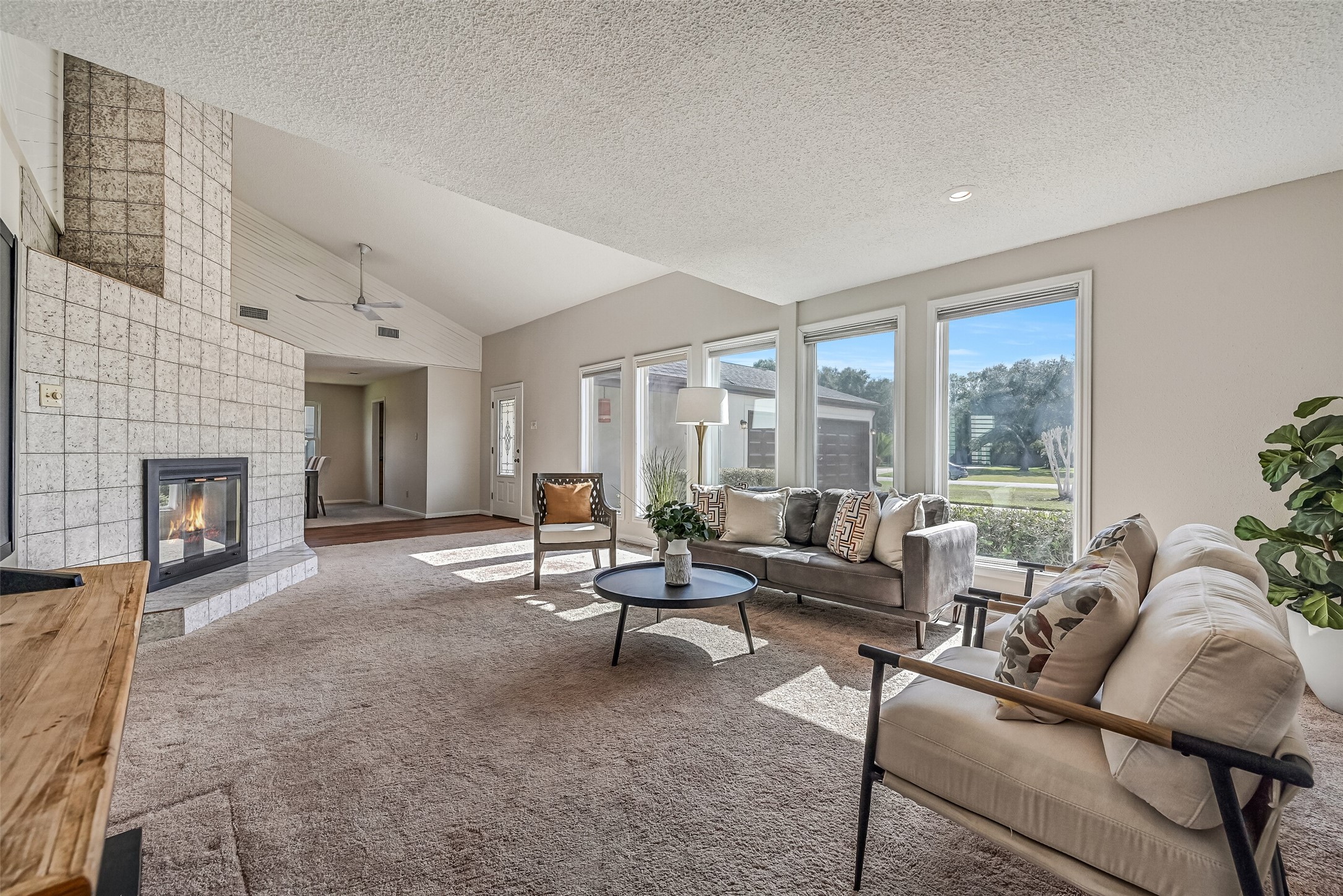 Sunlight pours through a wall of windows into this spacious two-story living room! A dramatic floor-to-ceiling tiled fireplace serves as the focal point, while soaring ceilings, neutral finishes & an upstairs loft overlooking the living area create an open, airy atmosphere.