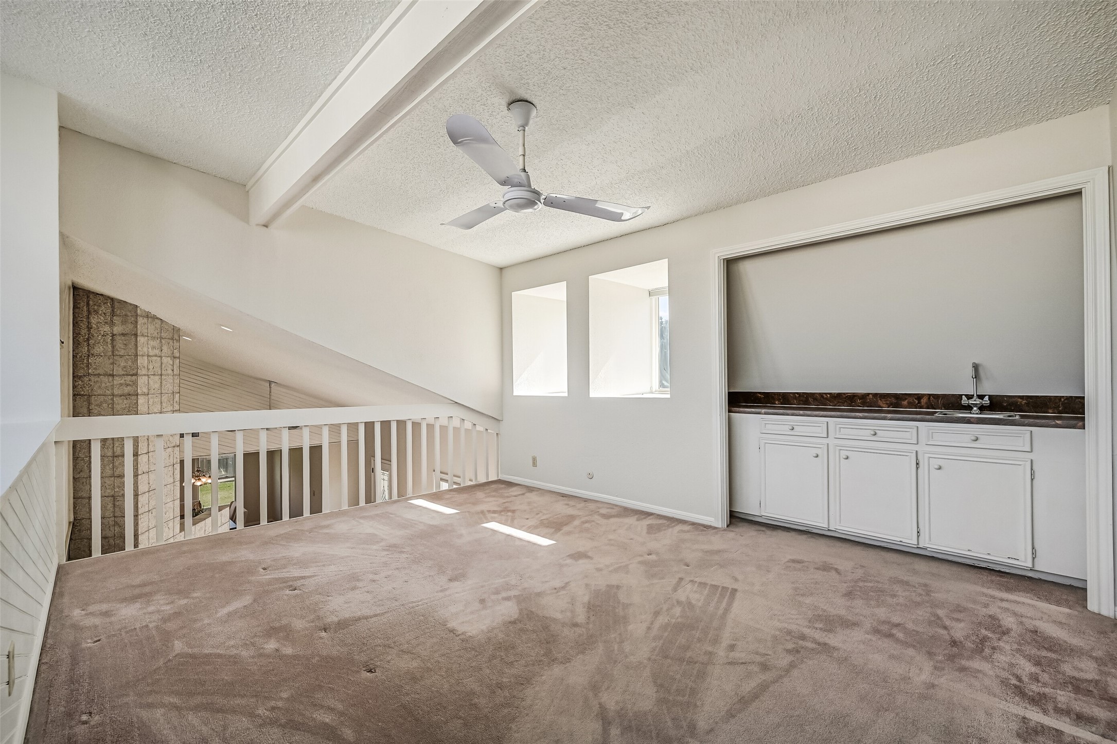 Overlooking the soaring living room and distinctive tiled fireplace, the upstairs loft offers an open, airy setting for entertaining or relaxing. A built-in wet bar with sink, countertop & storage cabinetry adds convenience, while interior openings and windows bring additional natural light into the space.