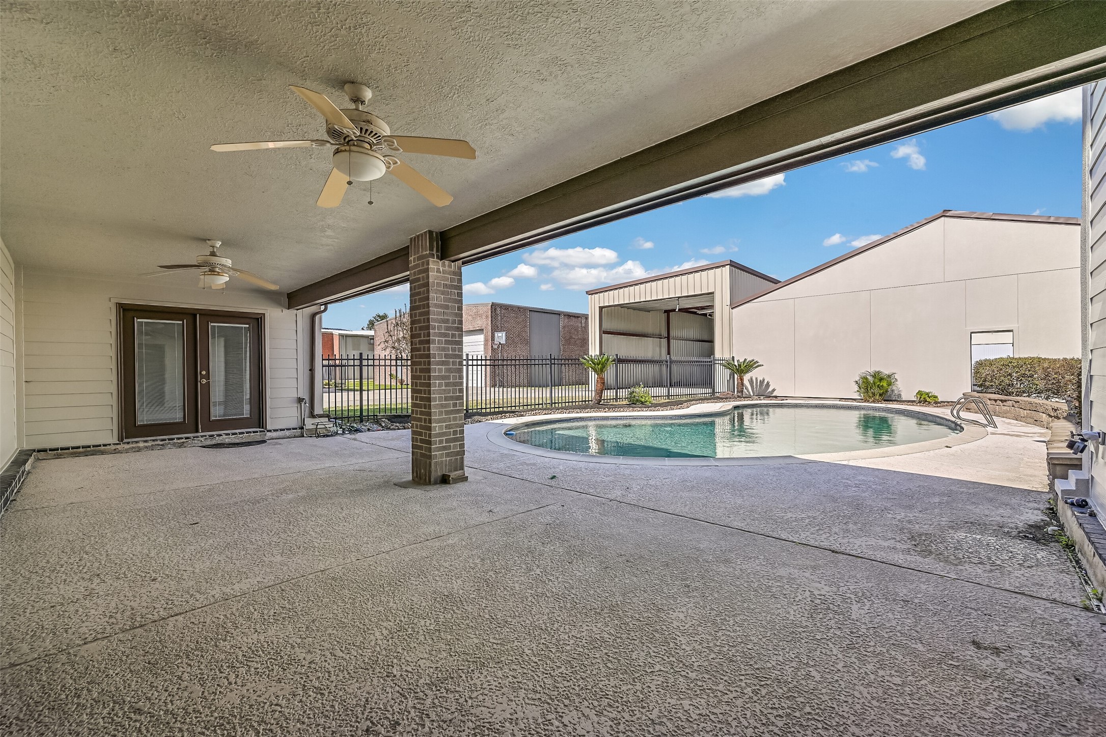 Enjoy outdoor living beneath the spacious covered patio featuring two ceiling fans, a textured concrete surface & plenty of room for seating and entertaining. The backyard swimming pool is just steps away, while French doors from both the primary suite and a secondary bedroom provide convenient access to the covered patio and backyard pool.
