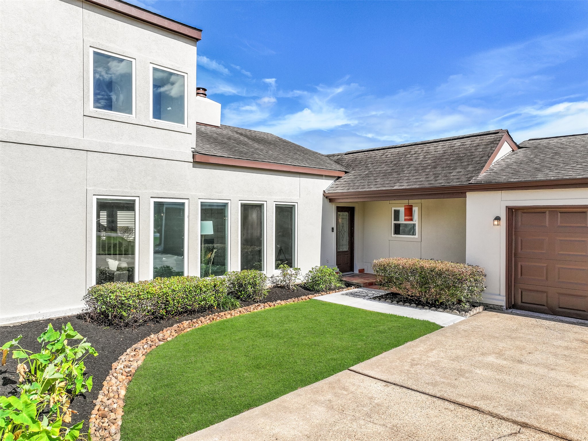 A closer look at the welcoming front entrance reveals decorative glasswork in the entry door, a sheltered porch & neatly maintained landscaping. Tall windows bring natural light into the soaring living room, while the attached garage and convenient driveway provide easy access to the home.