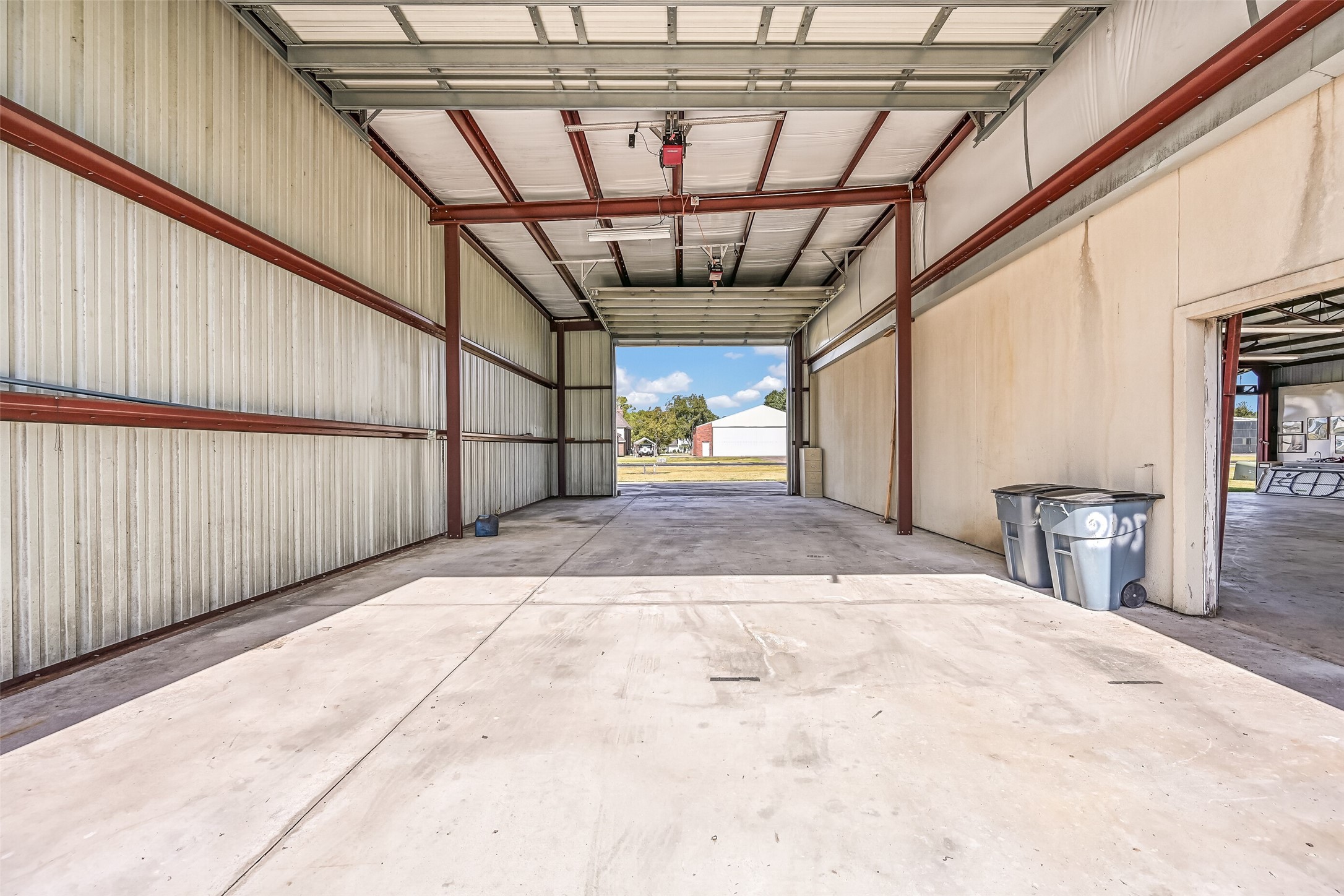 Inside the RV garage, you'll find a spacious open interior with concrete flooring, metal construction, RV power hookup, and overhead doors at both ends for convenient drive-through access. An interior passage connects directly to the adjoining airplane hangar, adding functionality to this impressive outbuilding.