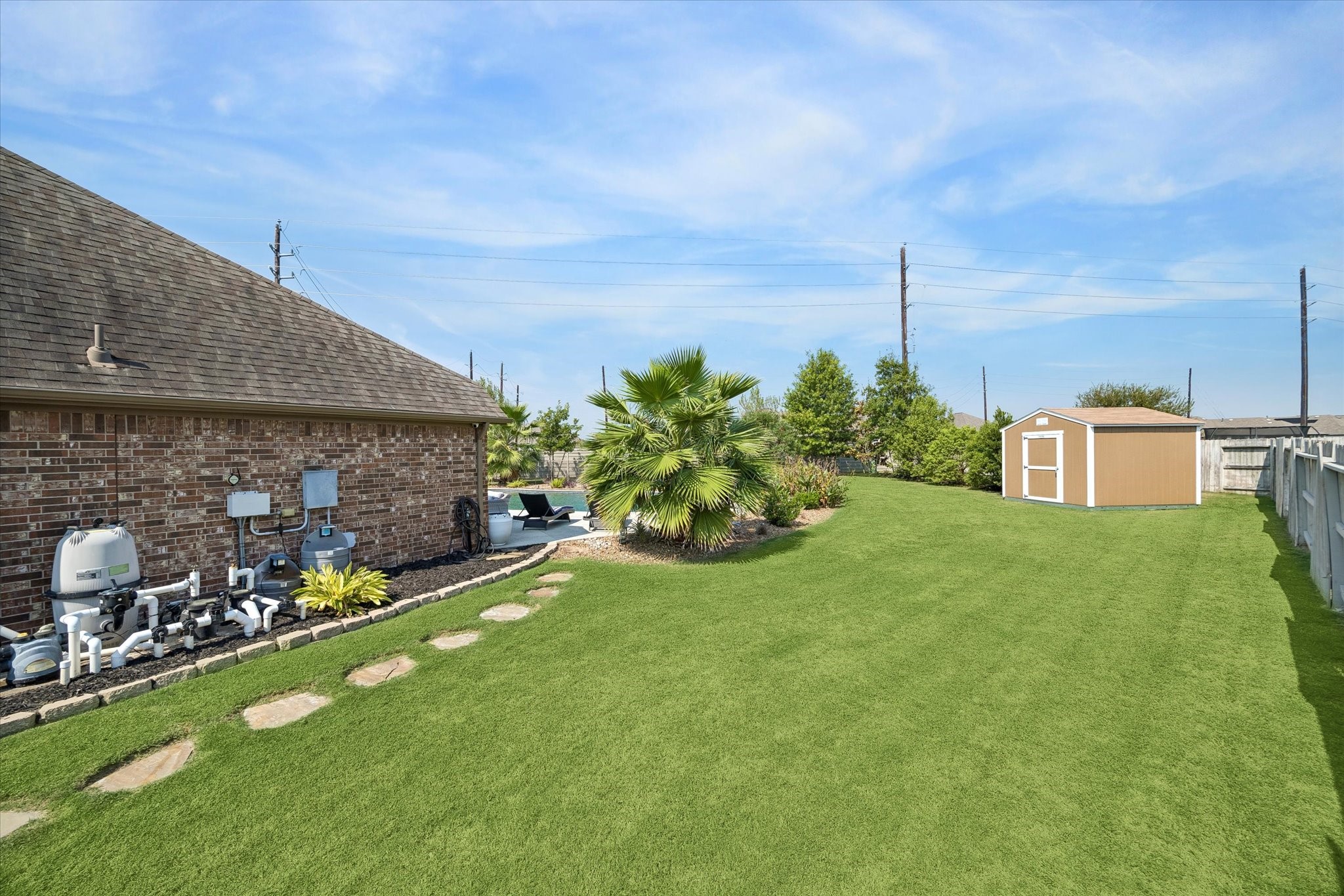 There is so much additional green space in this home! You can also see the dedicated storage shed perfect for housing extra gardening equipment and pool toys in the backyard. You'll also note the commercial grade pool equipment.
