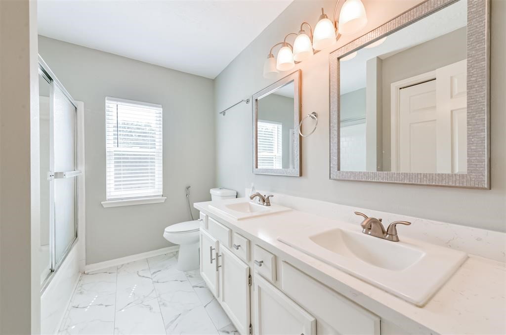 Double the convenience: This stylish secondary bathroom boasts dual sinks, offering a touch of luxury and functionality for your daily routine