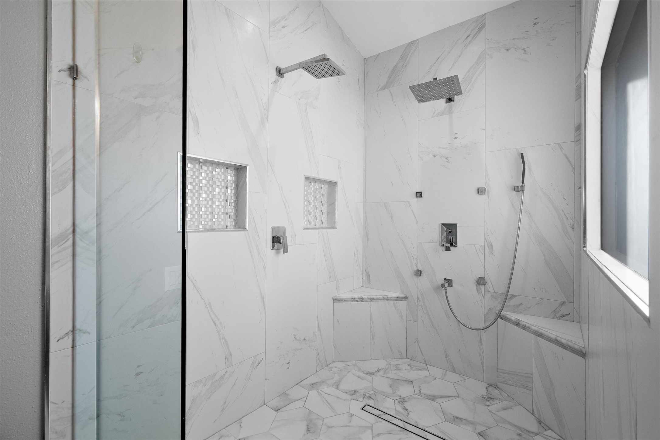 Large walk-in glass shower with dual showerhead fixtures.