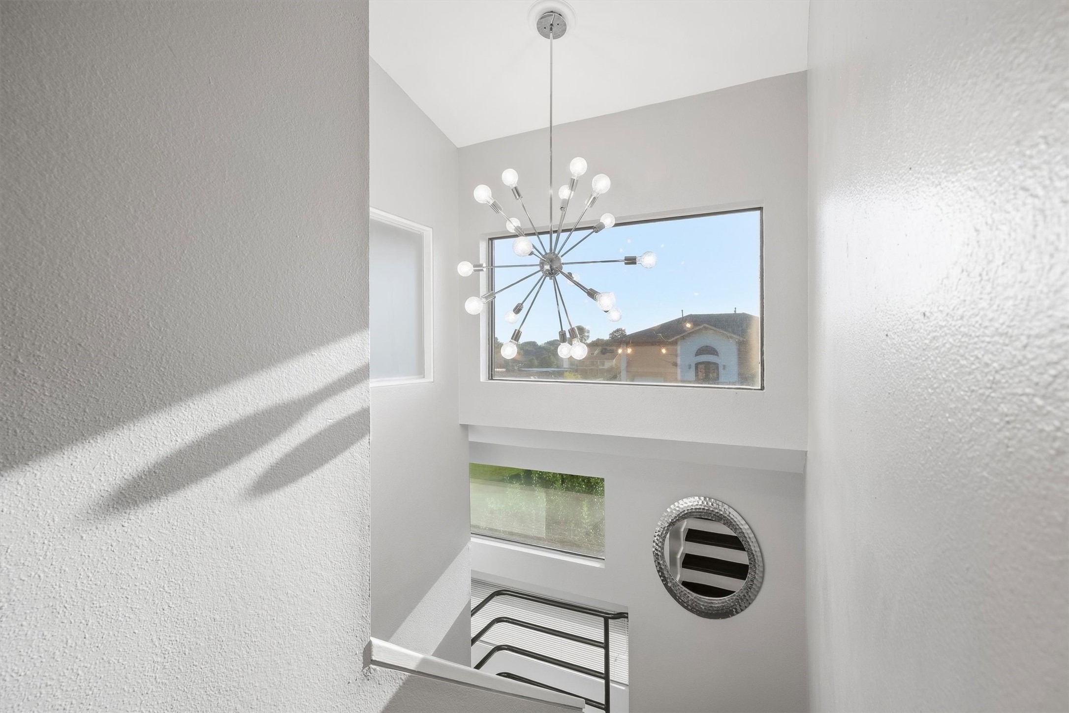 Statement modern chandelier illuminating the upper landing.