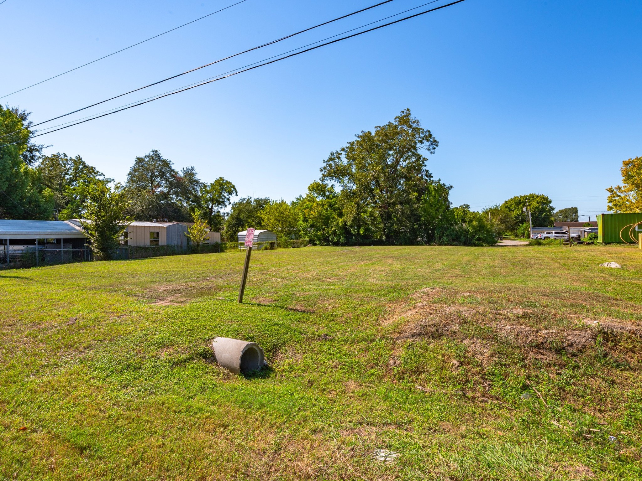 Ground-level view across the grassy lot toward the rear tree line. Ground-level view across the grassy lot toward the rear tree line.
