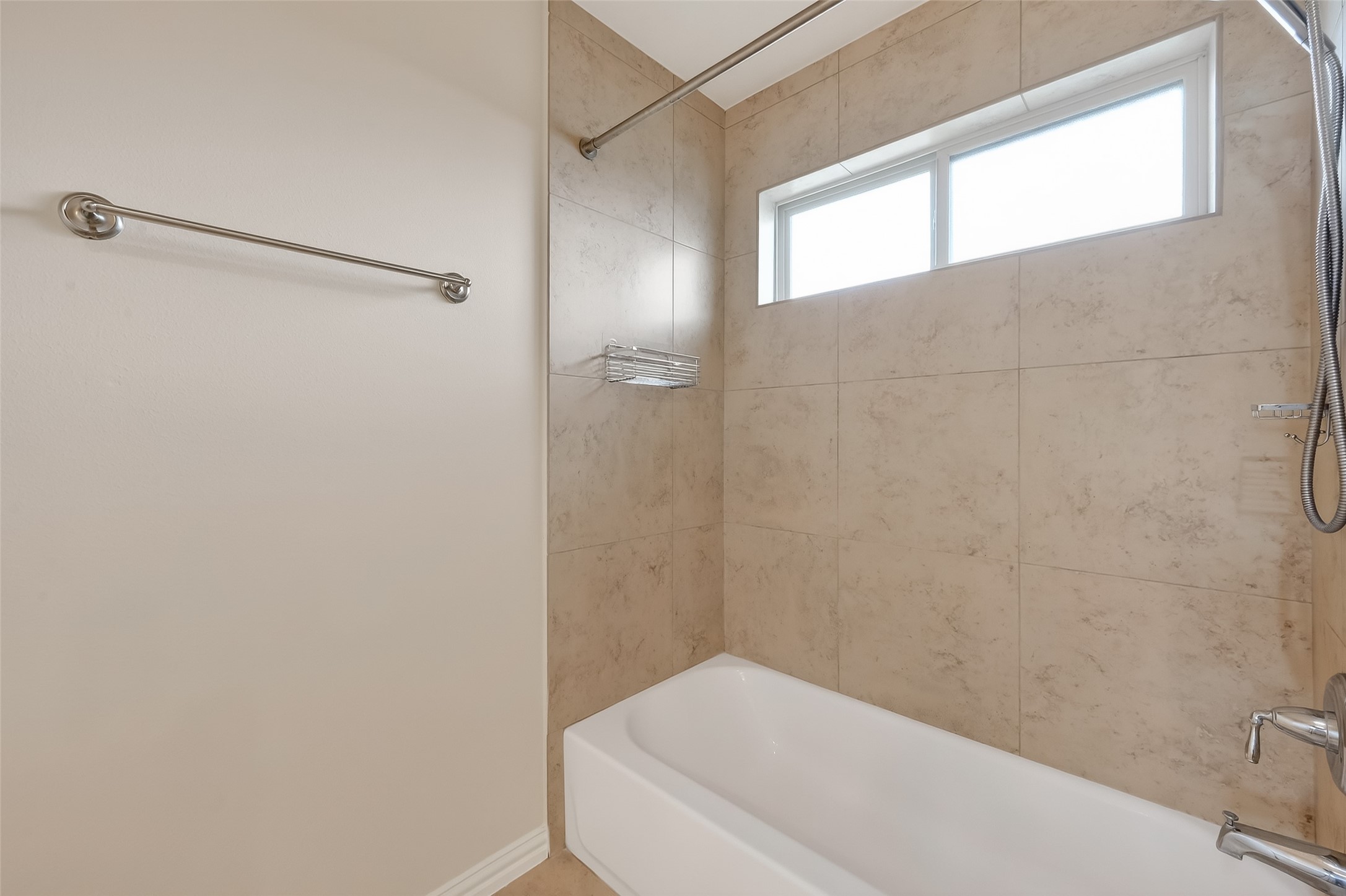 This shared bathroom offers a tub, tiled walls and clerestory windows that allow natural light in.