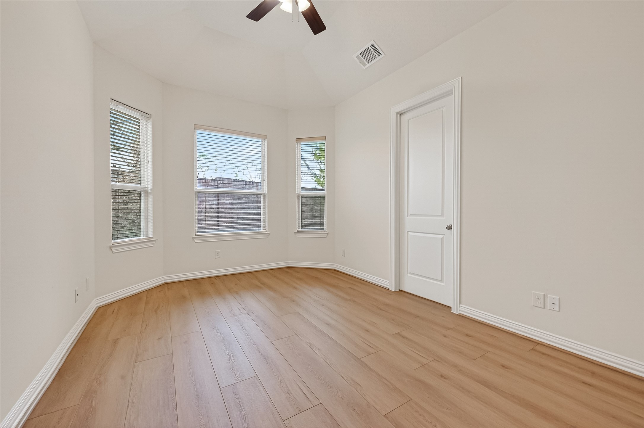 The downstairs secondary bedroom features high ceilings, a soft neutral palette, and abundant natural light. Large double-pane windows with plantation shutters frame beautiful views of the backyard, creating a bright and comfortable retreat.