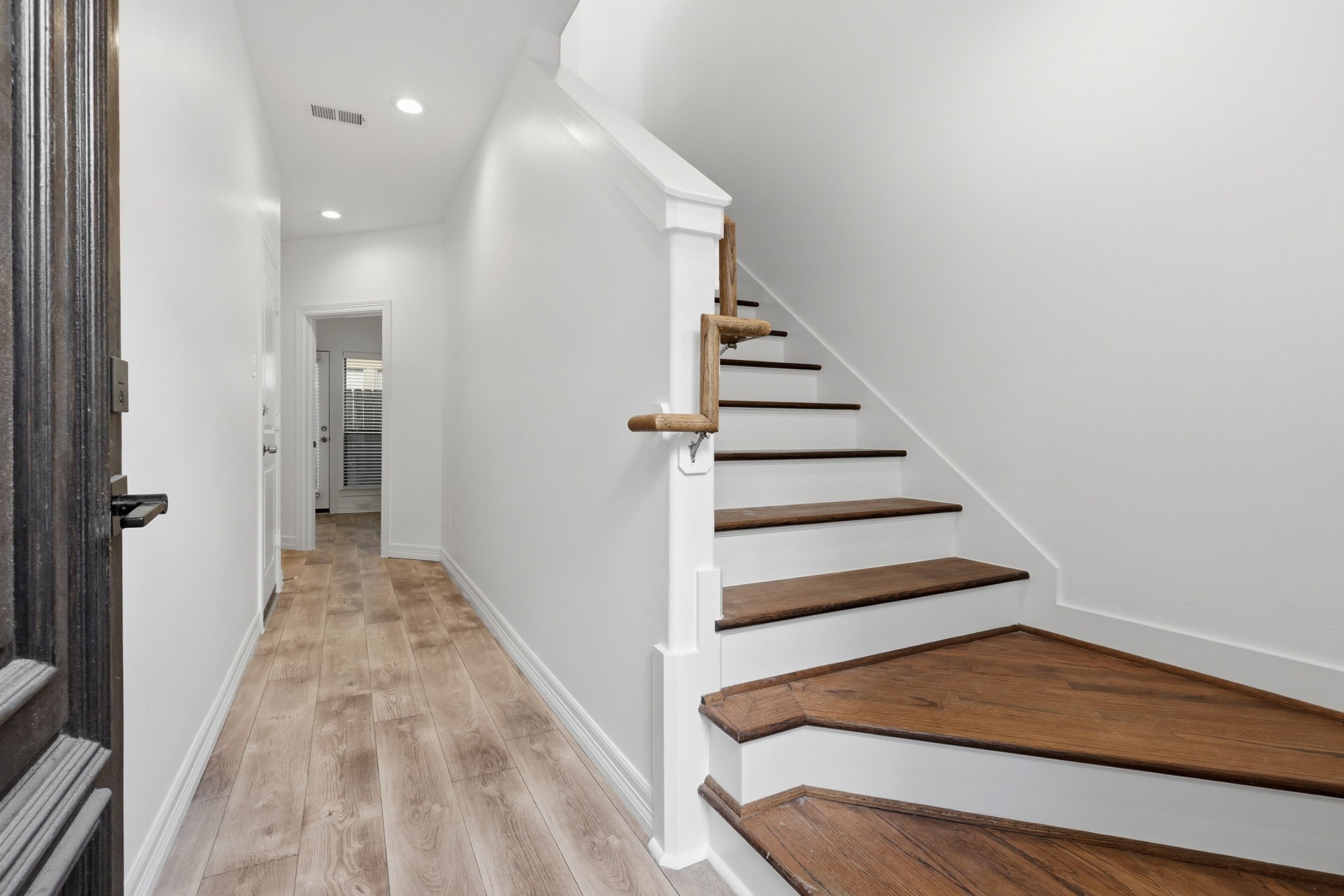 A welcoming entryway leads to a staircase with wood treads and crisp white risers, complemented by light-toned flooring and clean finishes for a polished first impression.
