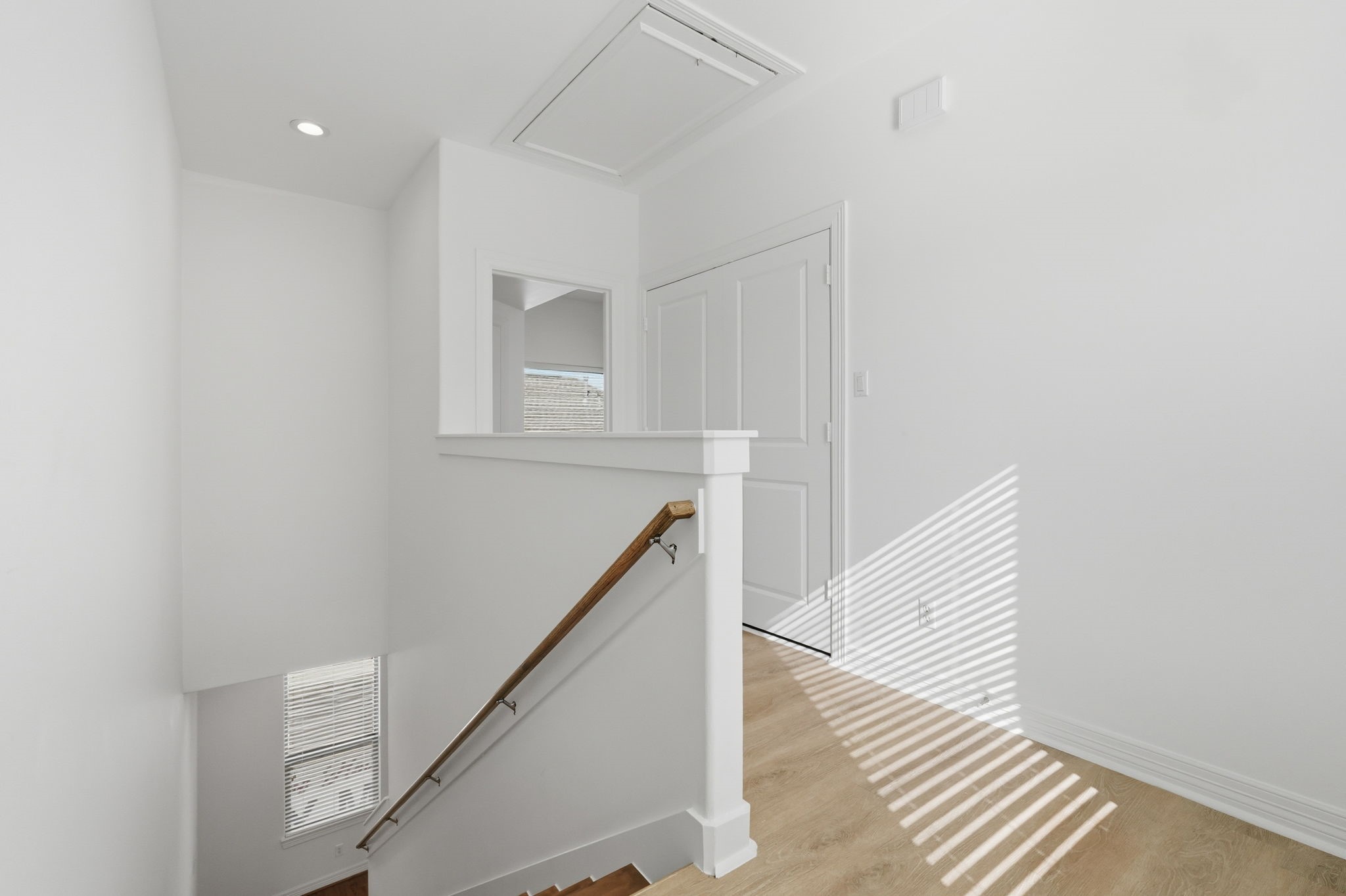 The upstairs landing features a clean, neutral design with white walls, a simple railing, and natural light filtering through nearby windows, creating a bright and welcoming transition between the upper-level rooms. (3rd floor)