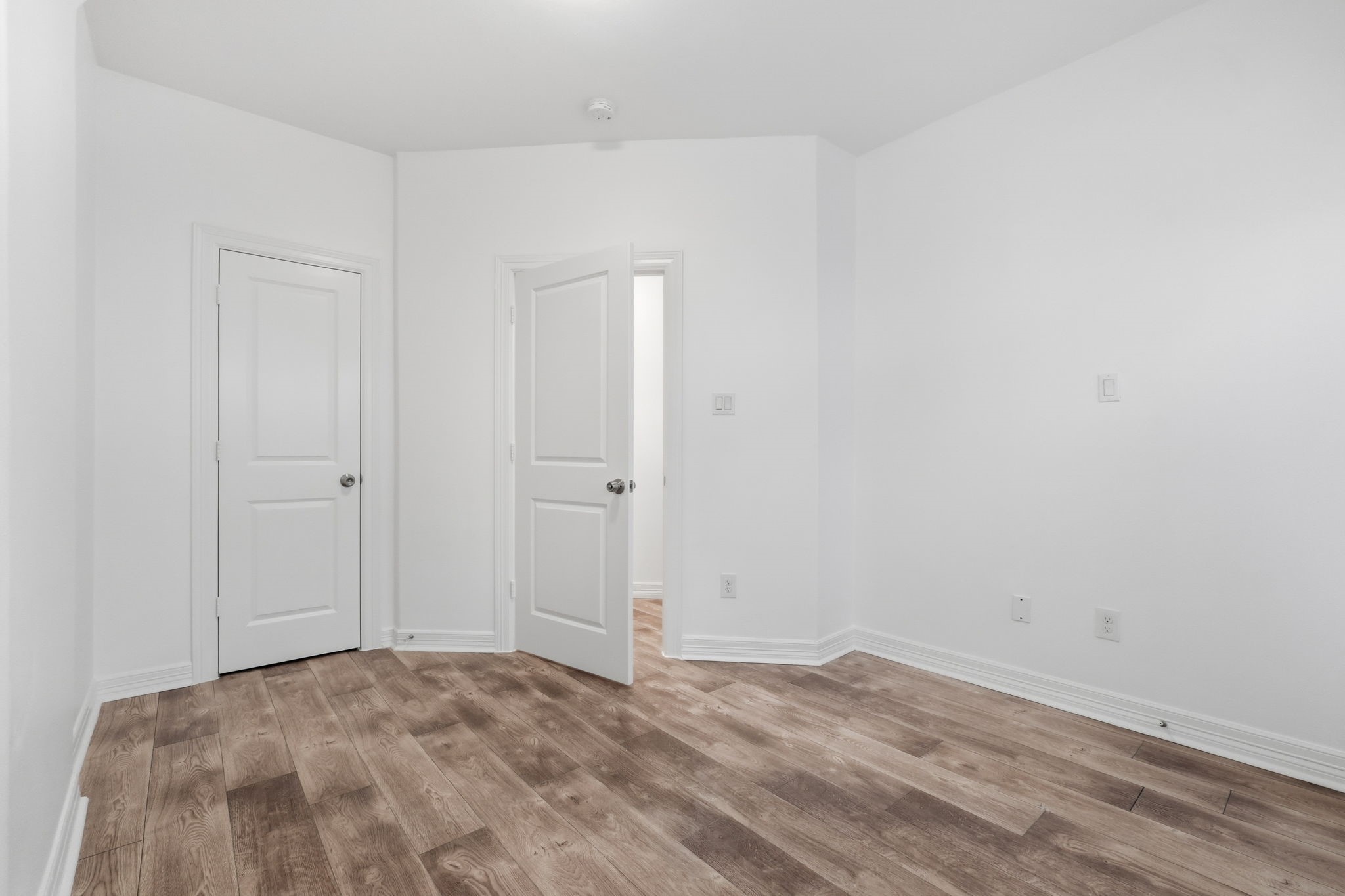Versatile room featuring neutral walls, wood-look flooring, and crisp white trim, offering flexibility for a variety of uses. (1st floor)