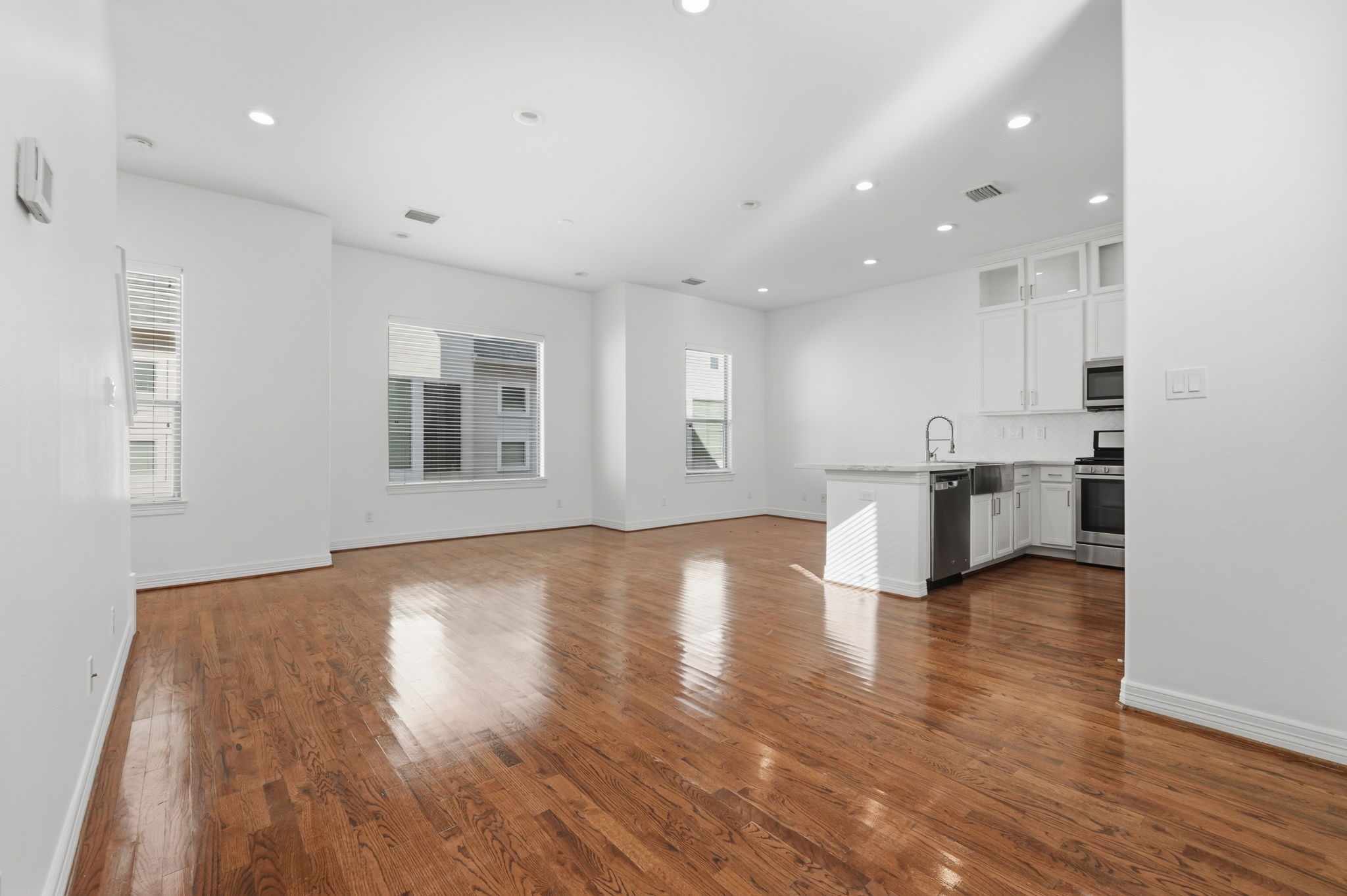 The expansive main living area showcases an open layout with a seamless connection to the kitchen, crisp interior finishes, and recessed lighting that enhances the homes bright, airy feel. (2nd floor)