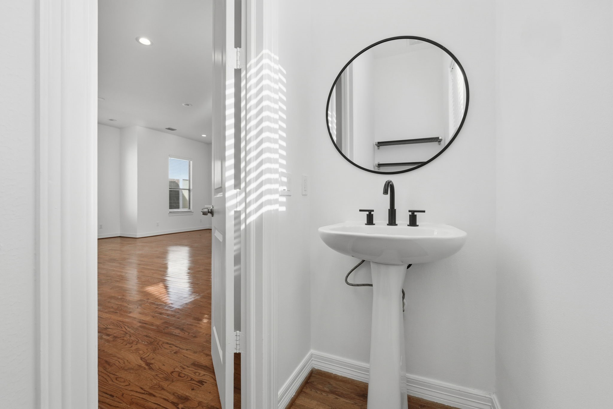A conveniently placed powder bath features a sleek pedestal sink, round mirror, and modern fixtures, with a clean, neutral design that complements the homes contemporary interior. (2nd floor)