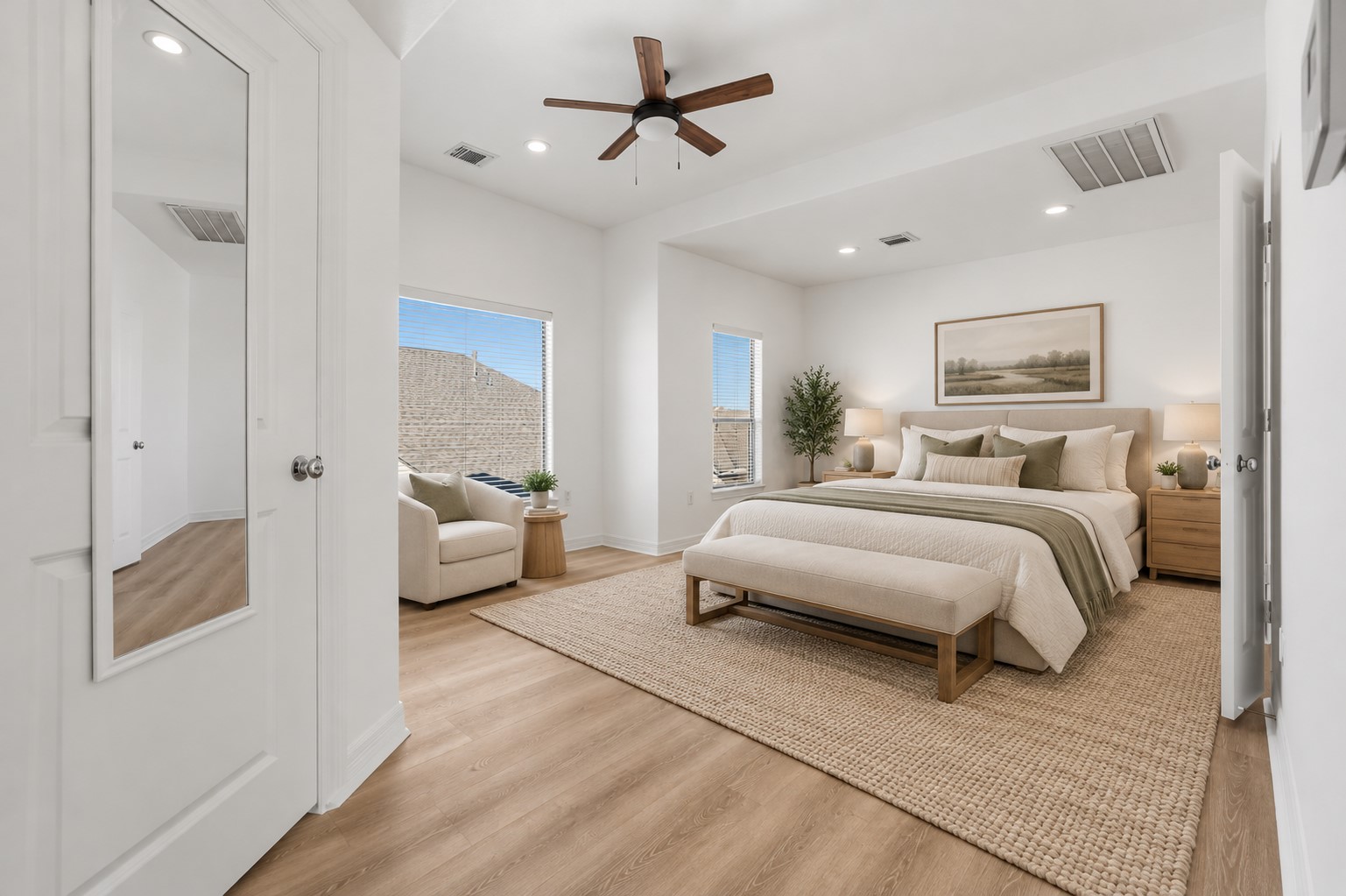 (Virtually staged) The primary bedroom features soft neutral tones, recessed lighting, and warm wood flooring, creating a bright and inviting atmosphere with a timeless appeal.