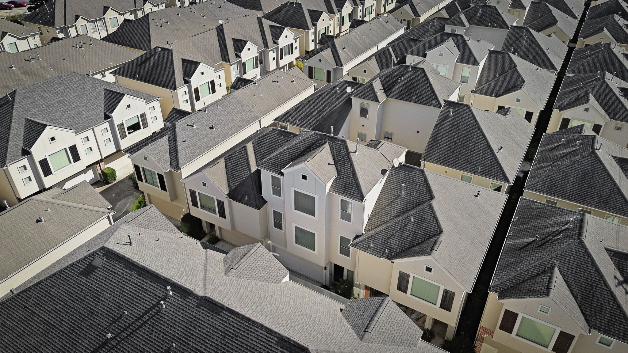An aerial perspective highlights the communitys uniform architectural style, with multi-story homes, coordinated rooflines, and neatly arranged residences creating a cohesive neighborhood setting.