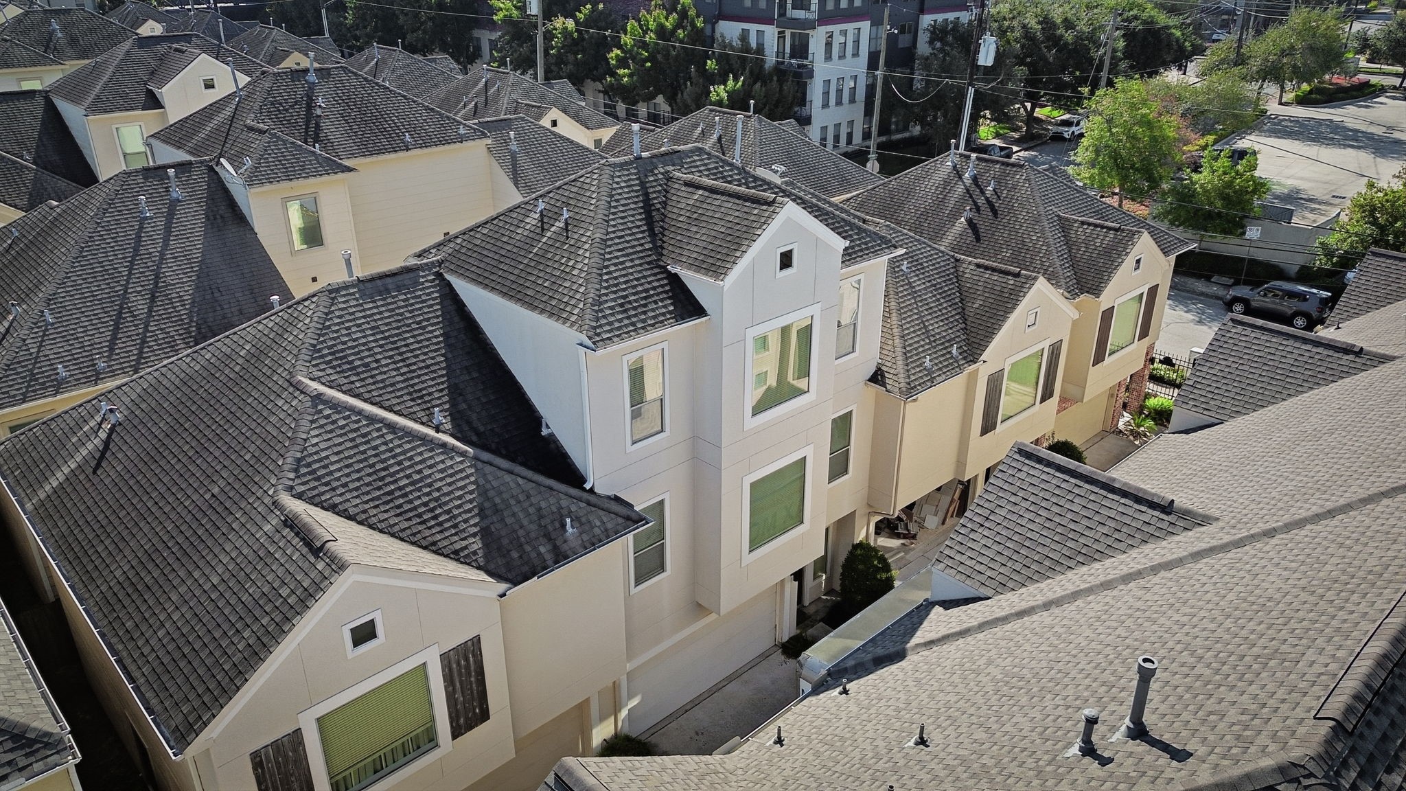 An aerial view showcases the homes multi-story exterior, featuring a distinctive roofline, neutral siding, and a cohesive architectural style within a well-established residential community.