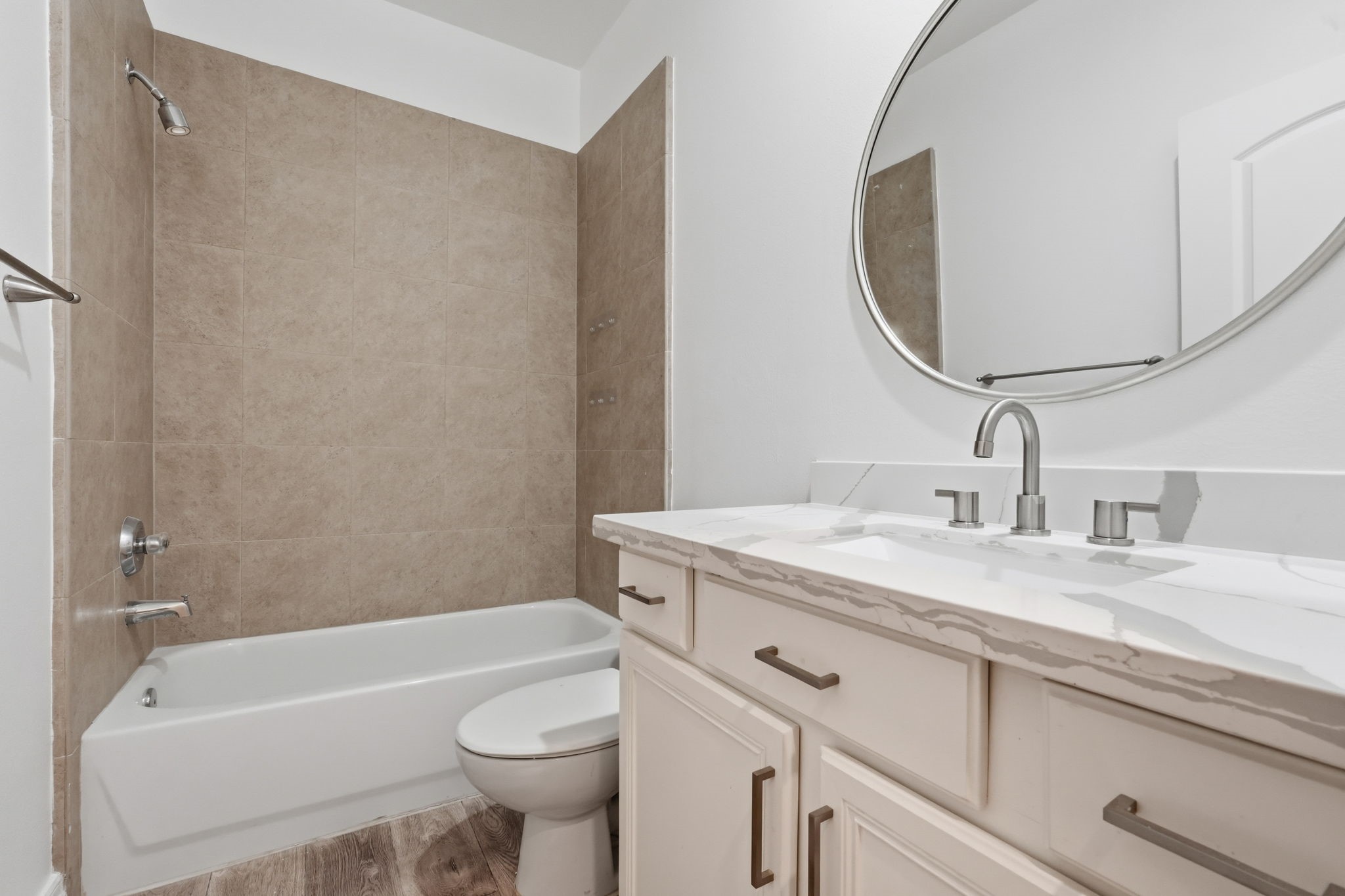 The secondary bathroom features a tub and shower combination with neutral tile surrounds, a spacious vanity, and a large mirror, blending clean finishes with everyday functionality. (1st floor)