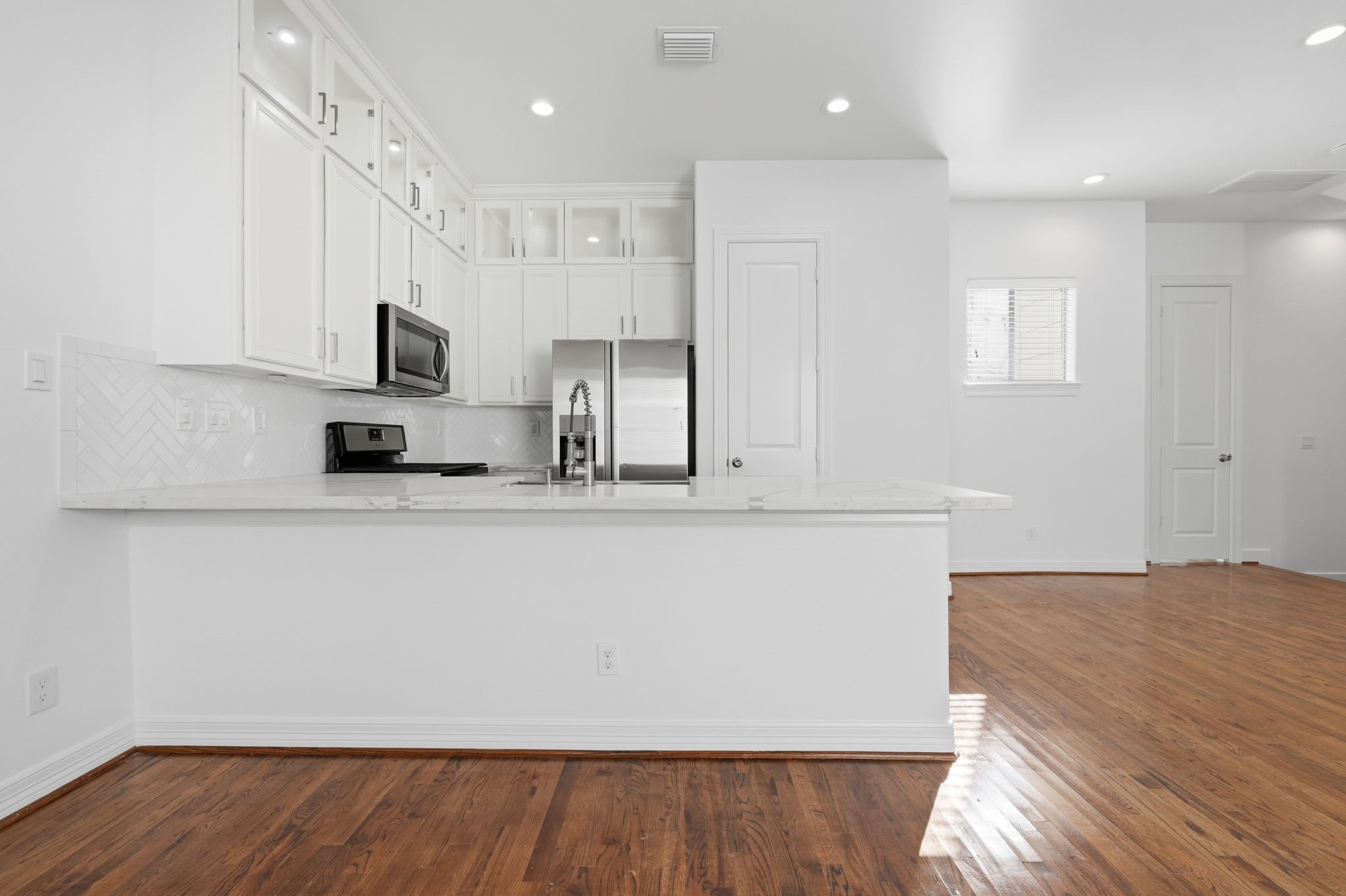 A thoughtfully designed kitchen features ceiling-height cabinetry, a decorative herringbone backsplash, and generous counter space, with stainless steel appliances and a breakfast bar that seamlessly connects to the surrounding living area. (2nd floor)