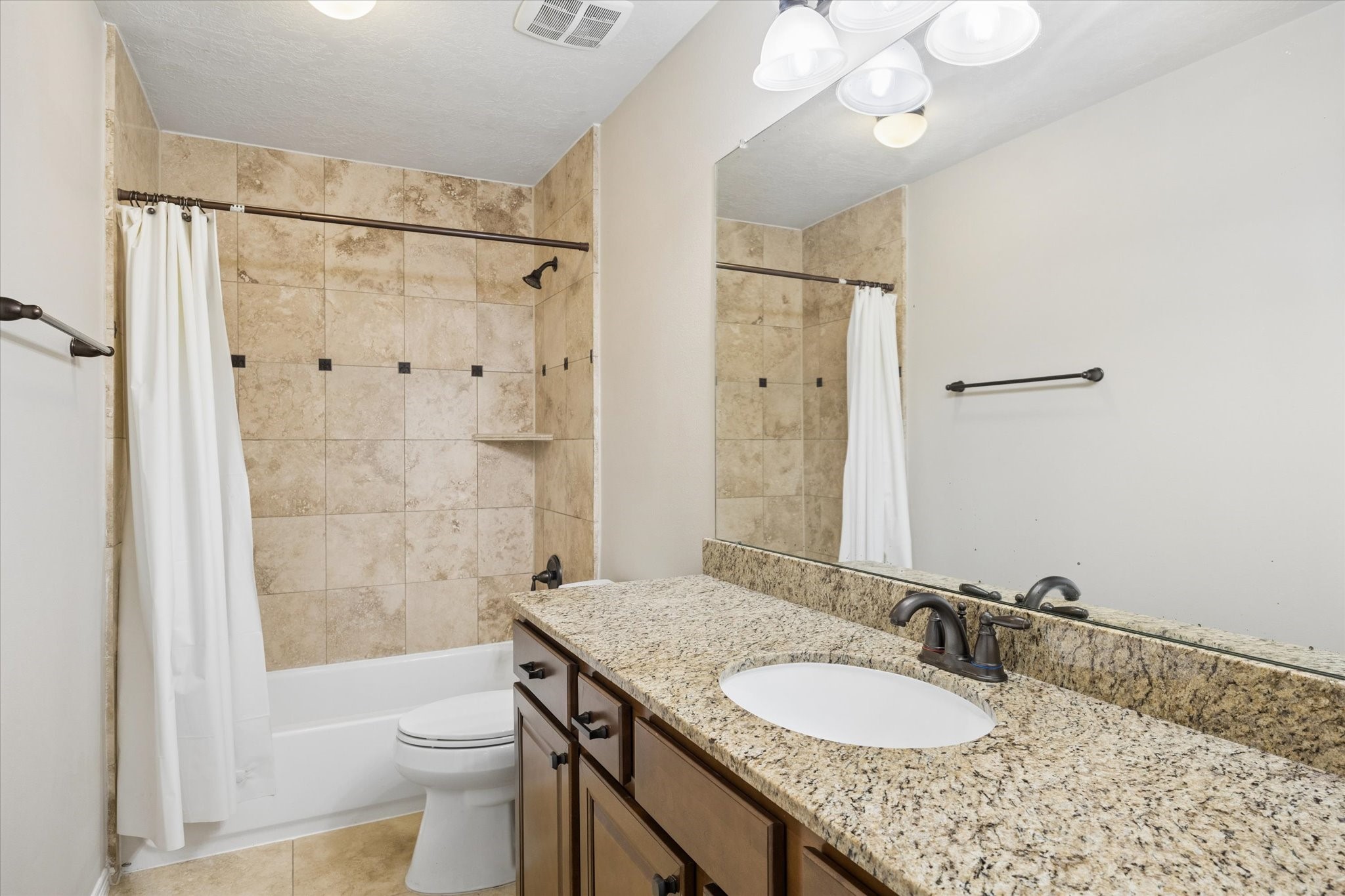 Private en-suite bathroom featuring a granite countertop and a tiled tub and shower combination, offering added comfort and convenience for family members or overnight guests.