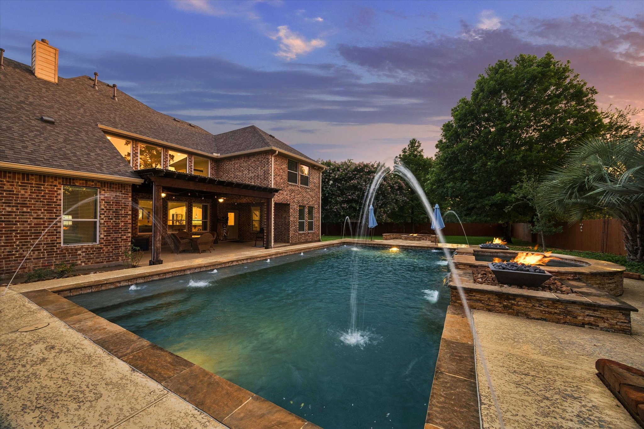 A captivating evening view showcasing the expansive pool, striking water features, and warm fire accents, creating a truly memorable backdrop for outdoor living and entertaining.