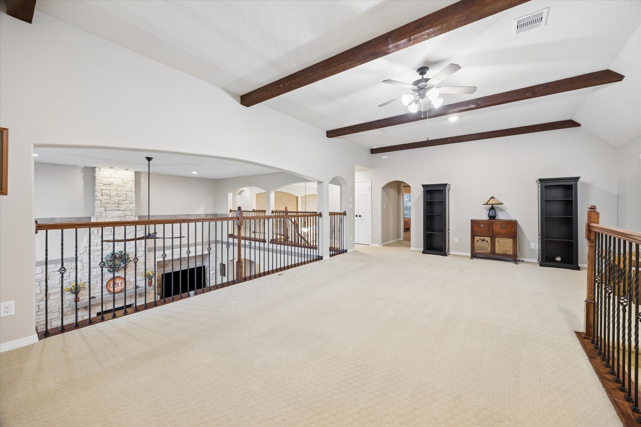 The expansive second-floor game room offers a versatile space for entertaining and relaxation, highlighted by vaulted ceilings with exposed wood beams and an open overlook to the family room below. Its generous proportions provide endless possibilities for a media area, billiards, or additional gathering space.