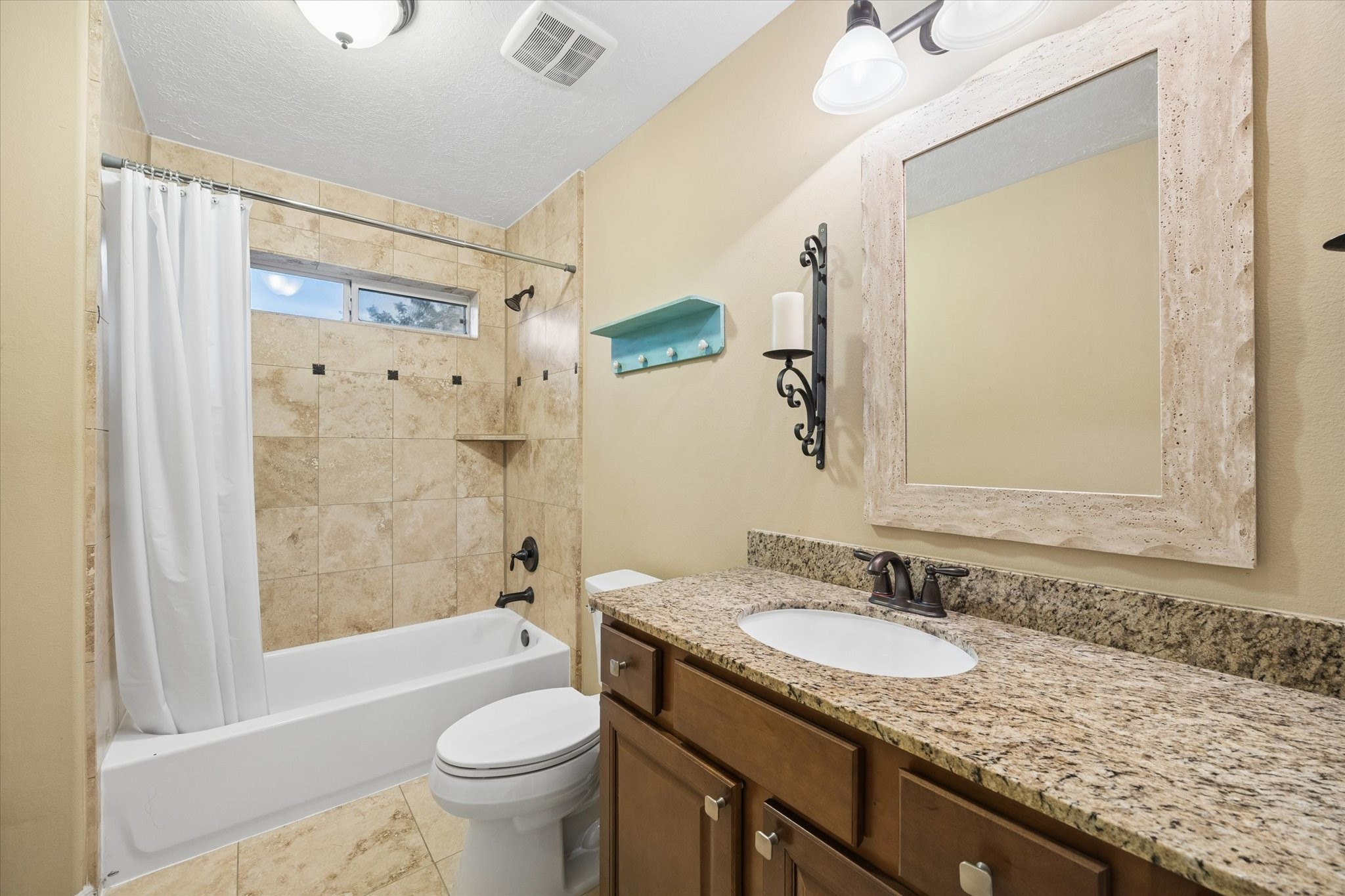 Well-appointed upstairs secondary bathroom featuring a granite-topped vanity and a beautifully tiled tub and shower combination.