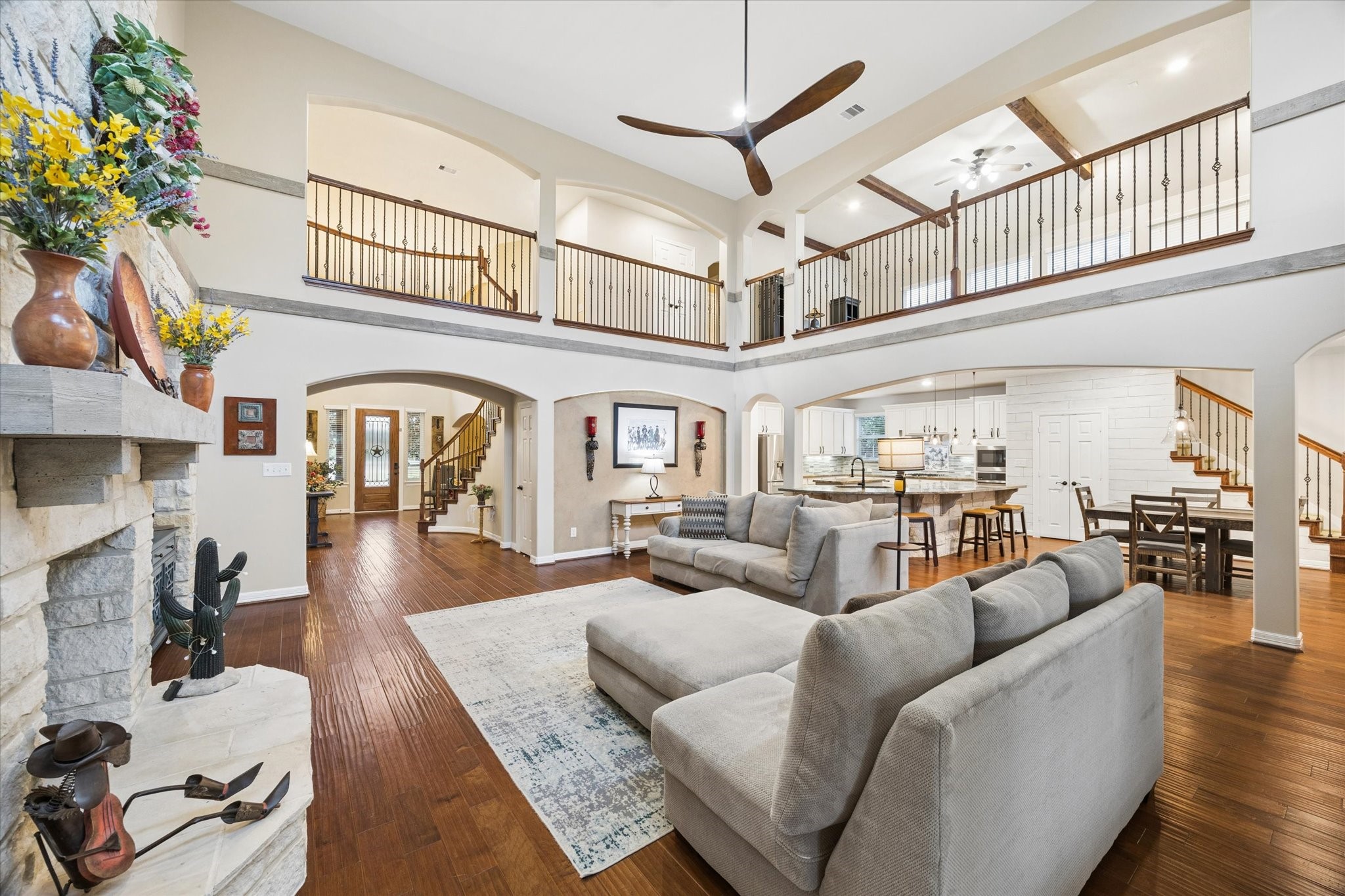 The impressive family room serves as the heart of the home, featuring soaring ceilings, rich hardwood floors, striking wood accents, and a beautiful stone fireplace. The open-concept design offers views of the second-level gallery and flows seamlessly into the kitchen and breakfast area, creating an exceptional setting for everyday living and entertaining.