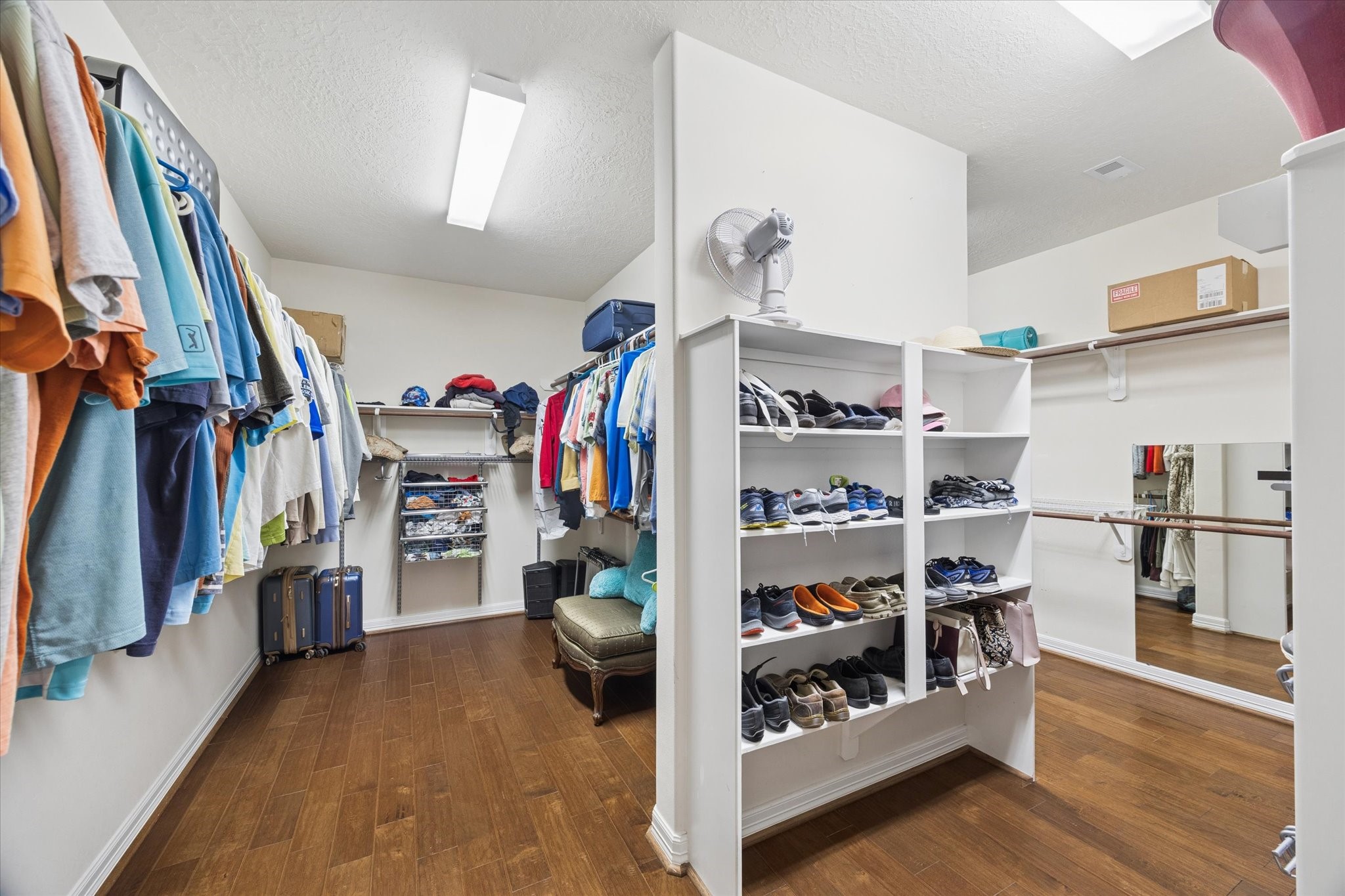 The generously sized primary walk-in closet offers exceptional storage with extensive hanging space, built-in shelving, and dedicated areas for shoes and accessories. The well-designed layout provides ample room to keep everything organized while maintaining an open and functional feel.