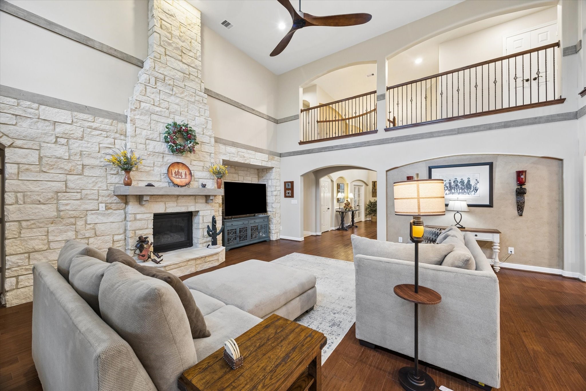 A dramatic floor-to-ceiling stone fireplace creates a striking focal point in the expansive family room. Soaring ceilings, rich hardwood floors, and views of the second-level gallery enhance the homes impressive sense of space and architectural character.
